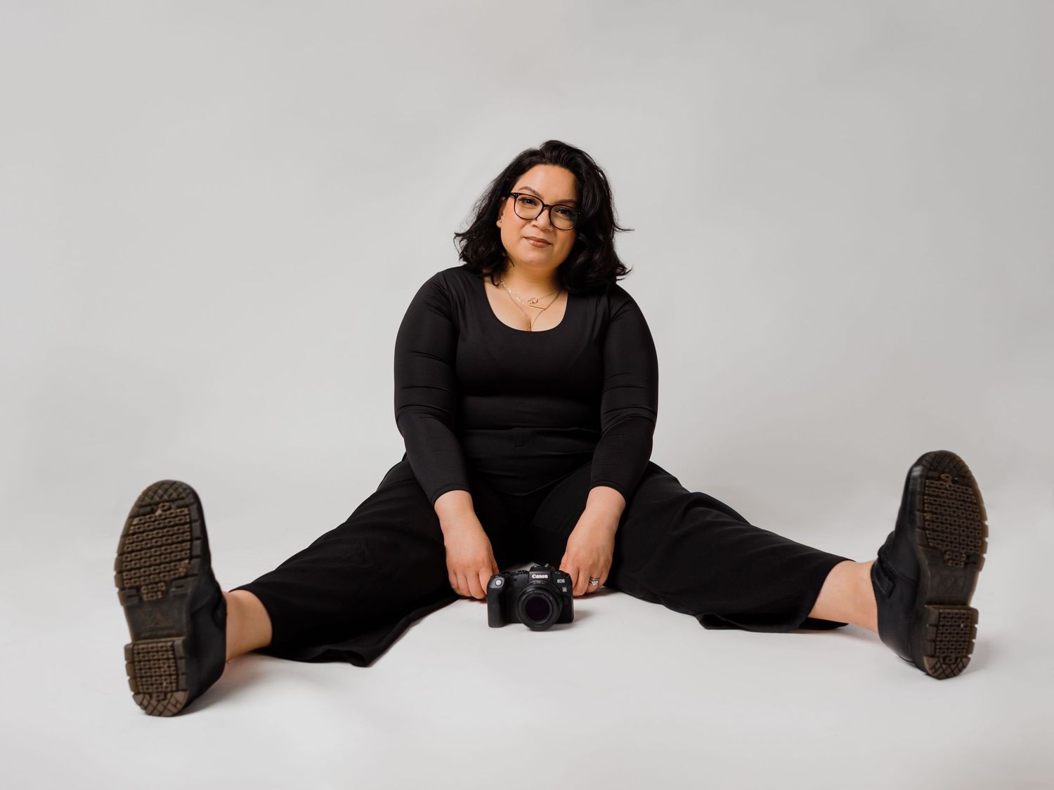 Casual studio portraits showing relaxed floor poses in black outfit.