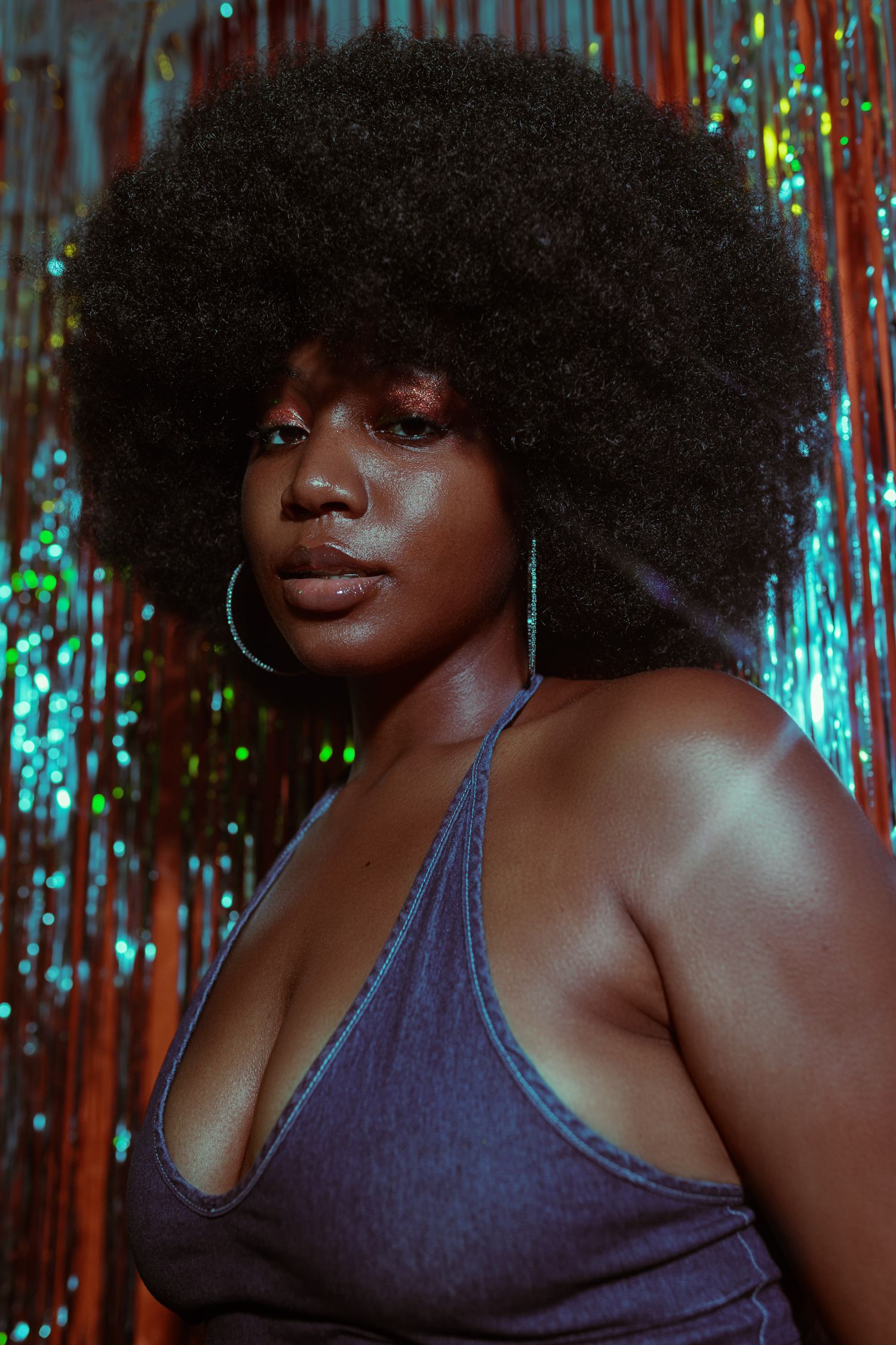 Close-up portrait with dramatic lighting against sparkly backdrop.