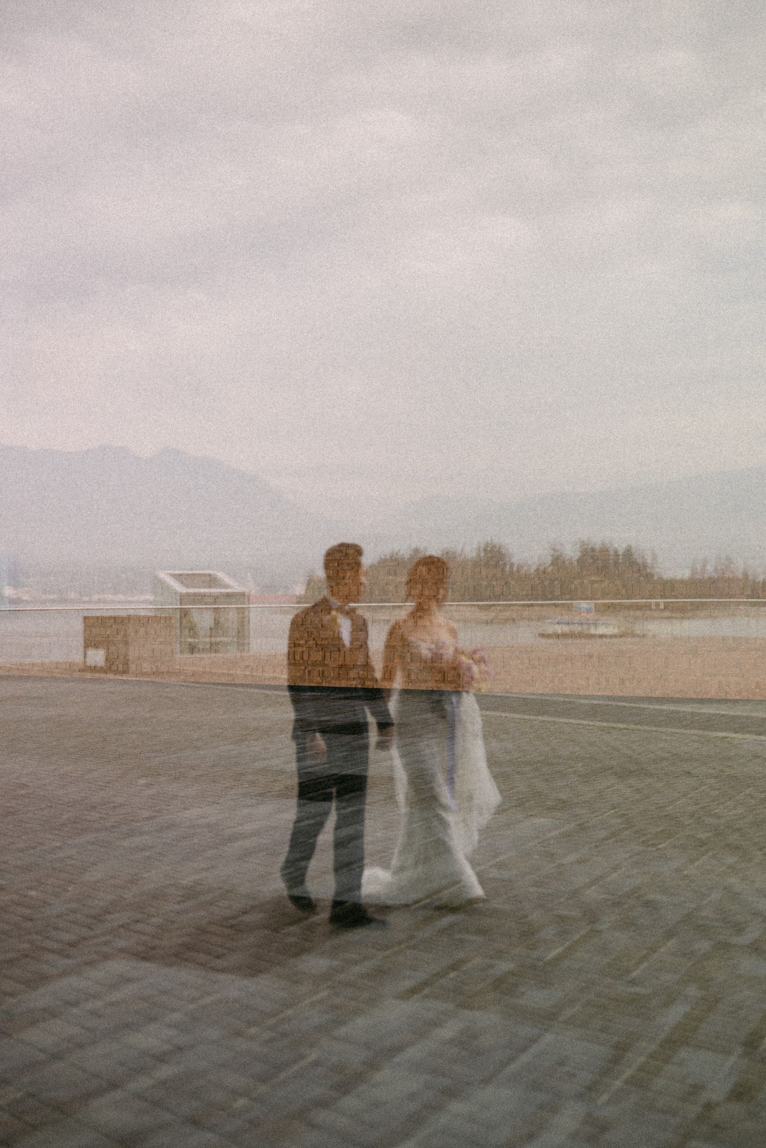 Reflection of bride and groom walking along Coal Harbour. Vancouver wedding by Victor Li Photography.