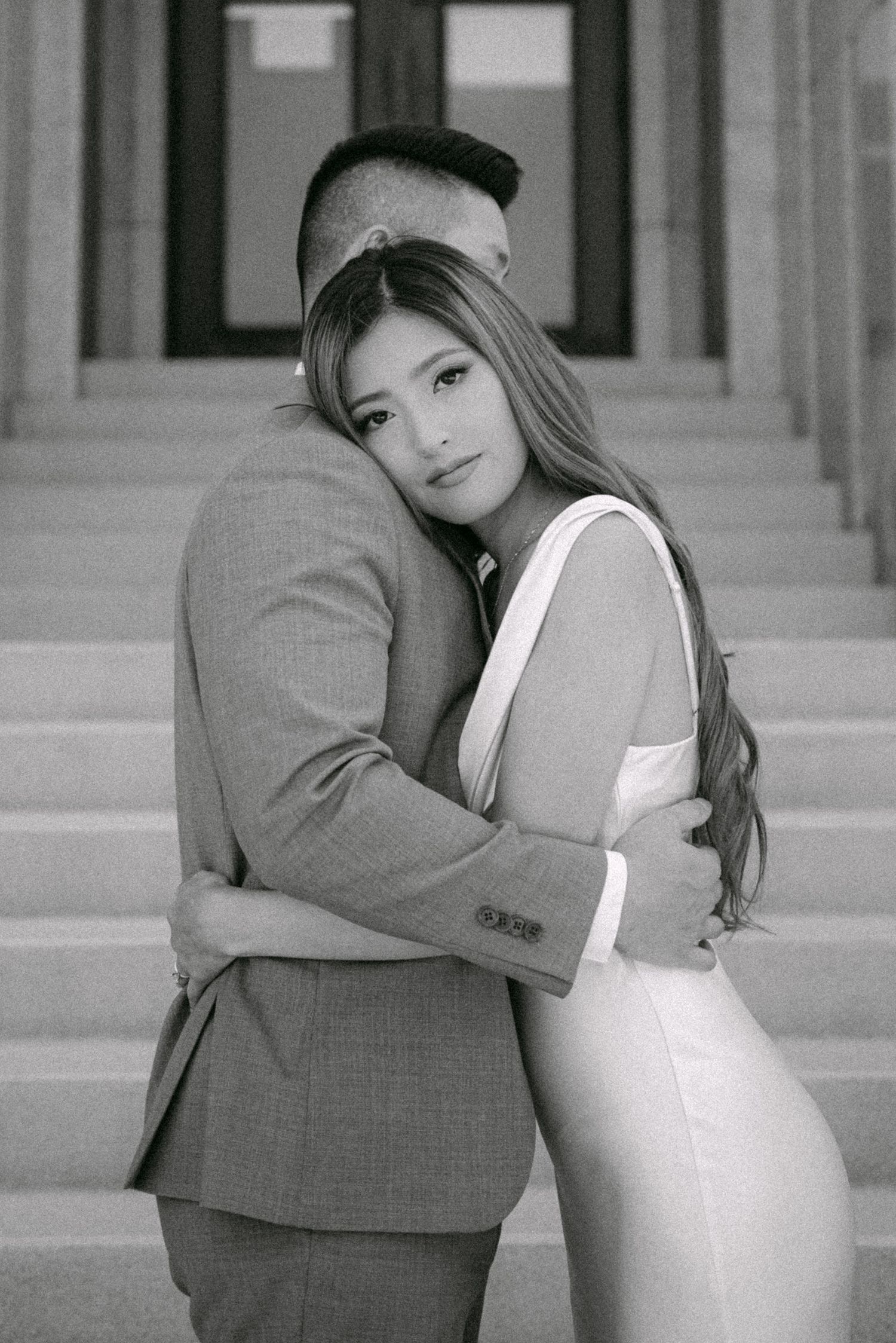 Bride embracing her groom on steps of Vancouver City Hall. Vancouver wedding by Victor Li Photography.