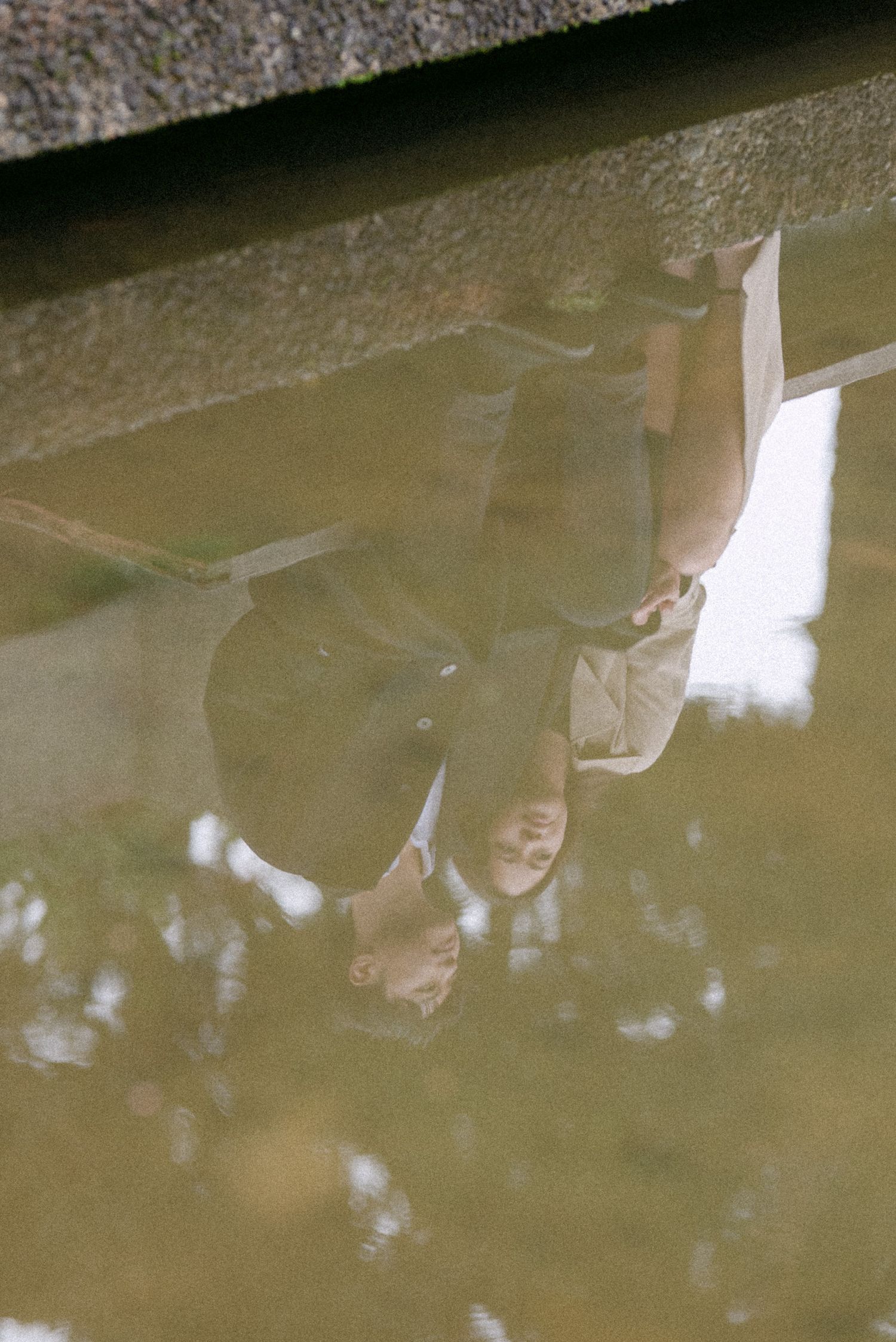 Reflection of couple sitting in UBC Rose Garden. Vancouver engagement by Victor Li Photography.