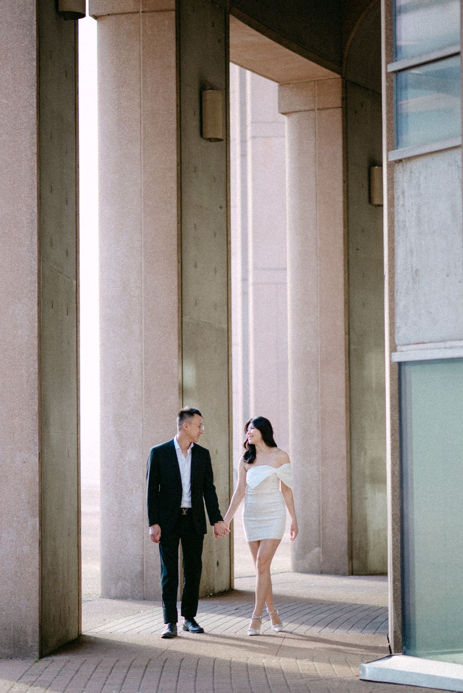 Couple walking between Vancouver Public Library columns. Vancouver prewedding and engagement by Victor Li Photography.