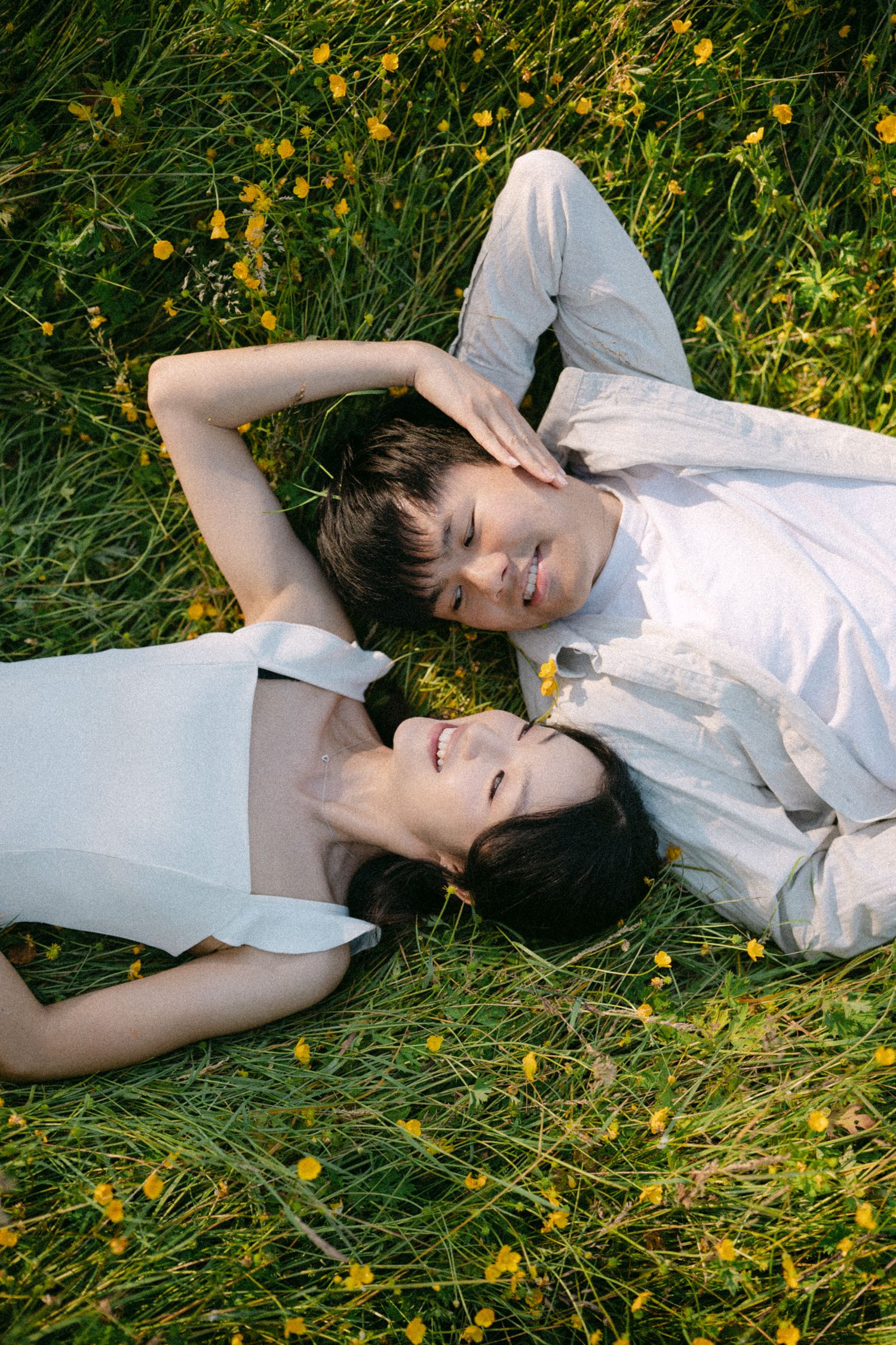Couple lying in grass at Terra Nova Park. Vancouver prewedding and engagement by Victor Li Photography.