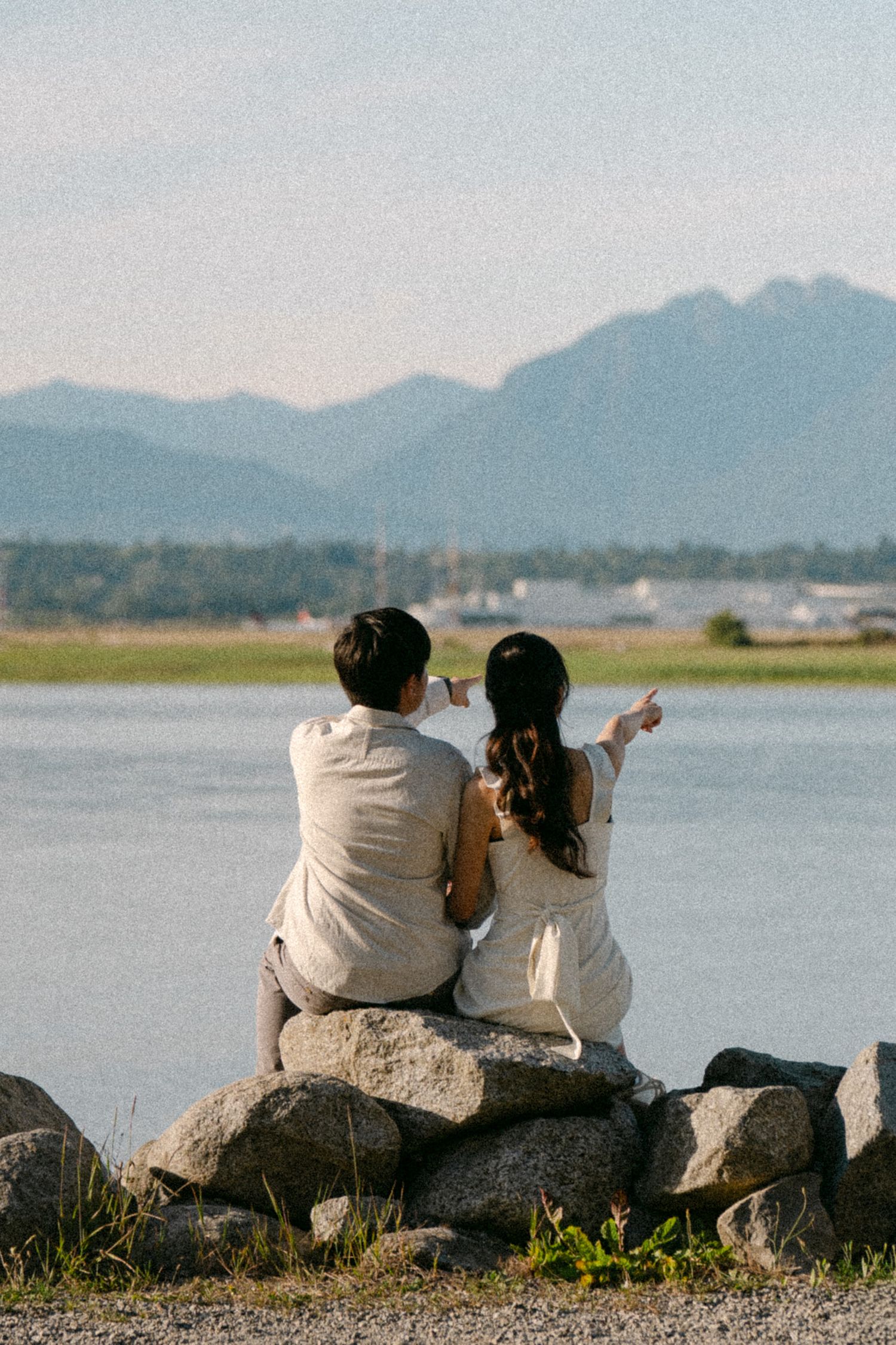 Couple sitting and pointing to far-off distant. Vancouver prewedding and engagement by Victor Li Photography.