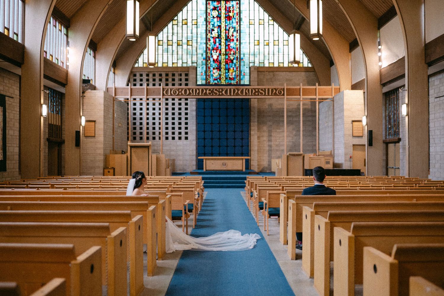 Couple sitting in church pews looking at altar. Vancouver wedding by Victor Li Photography.