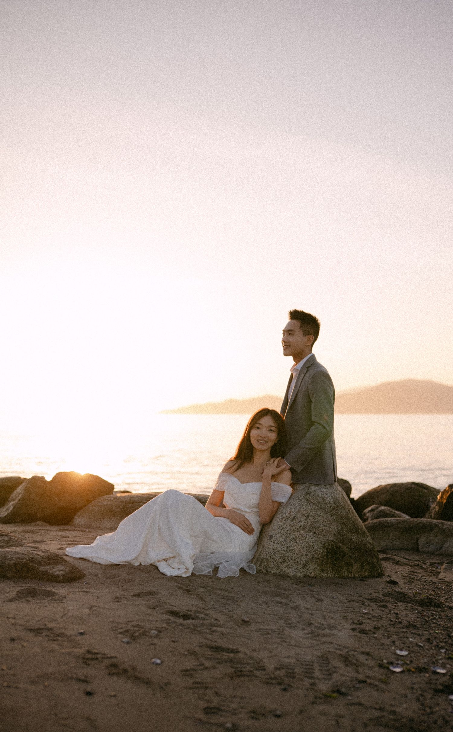 Couple sitting on rocks at Spanish Banks beach. Vancouver prewedding and engagement by Victor Li Photography.
