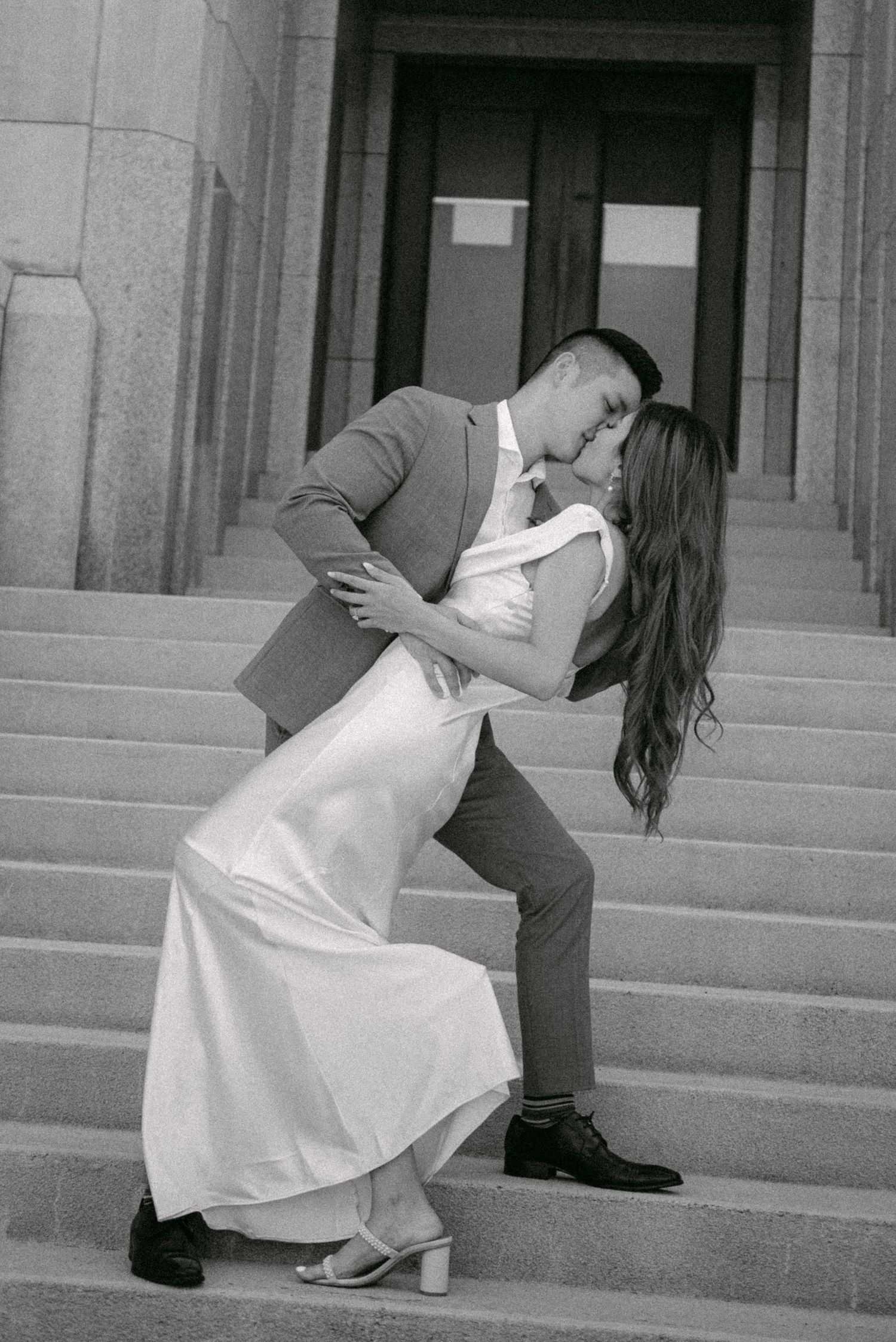 Bride and groom kisses on steps of Vancouver City Hall. Vancouver wedding by Victor Li Photography.