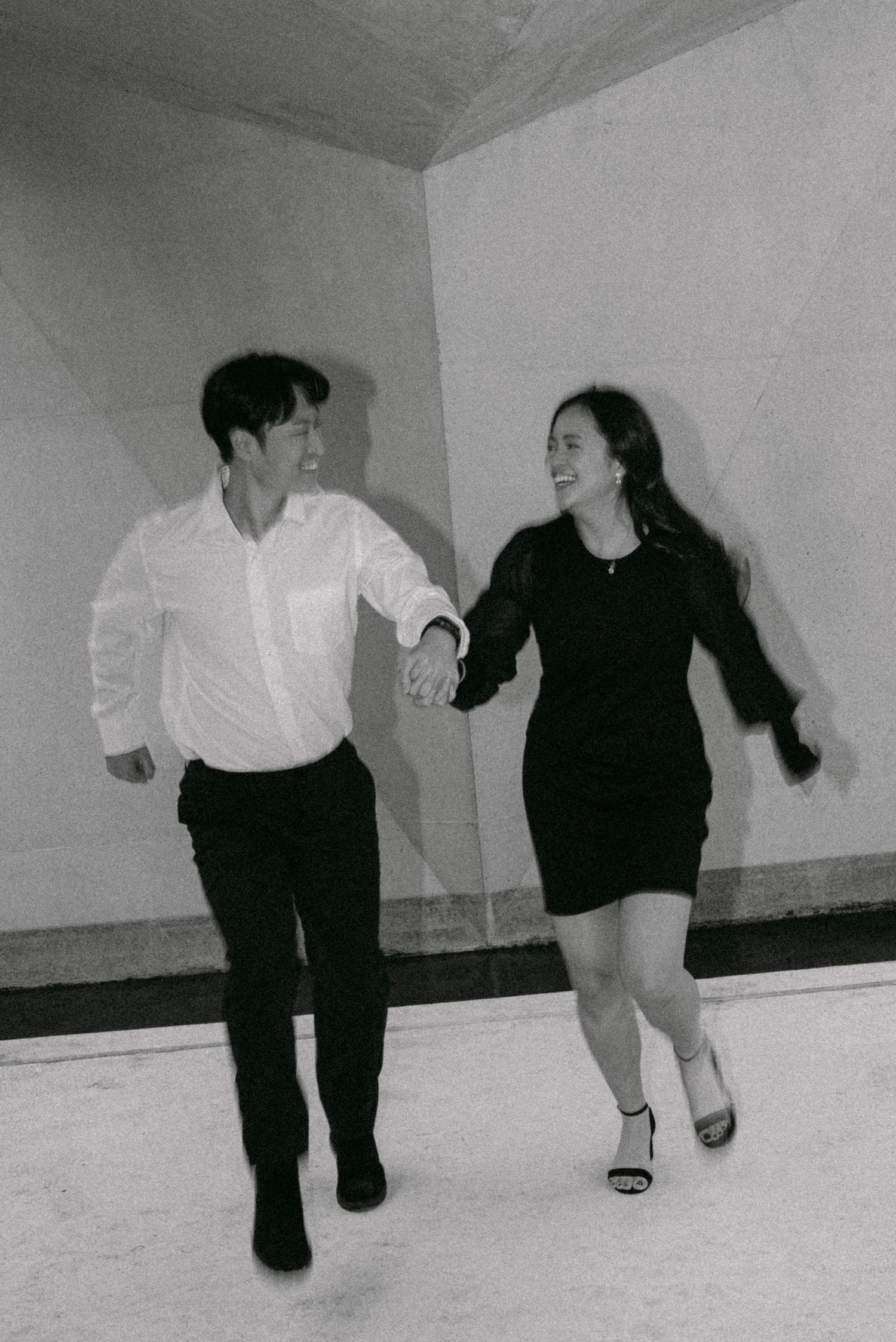 Couple running through UBC Buchanan Courtyard. Vancouver engagement by Victor Li Photography.