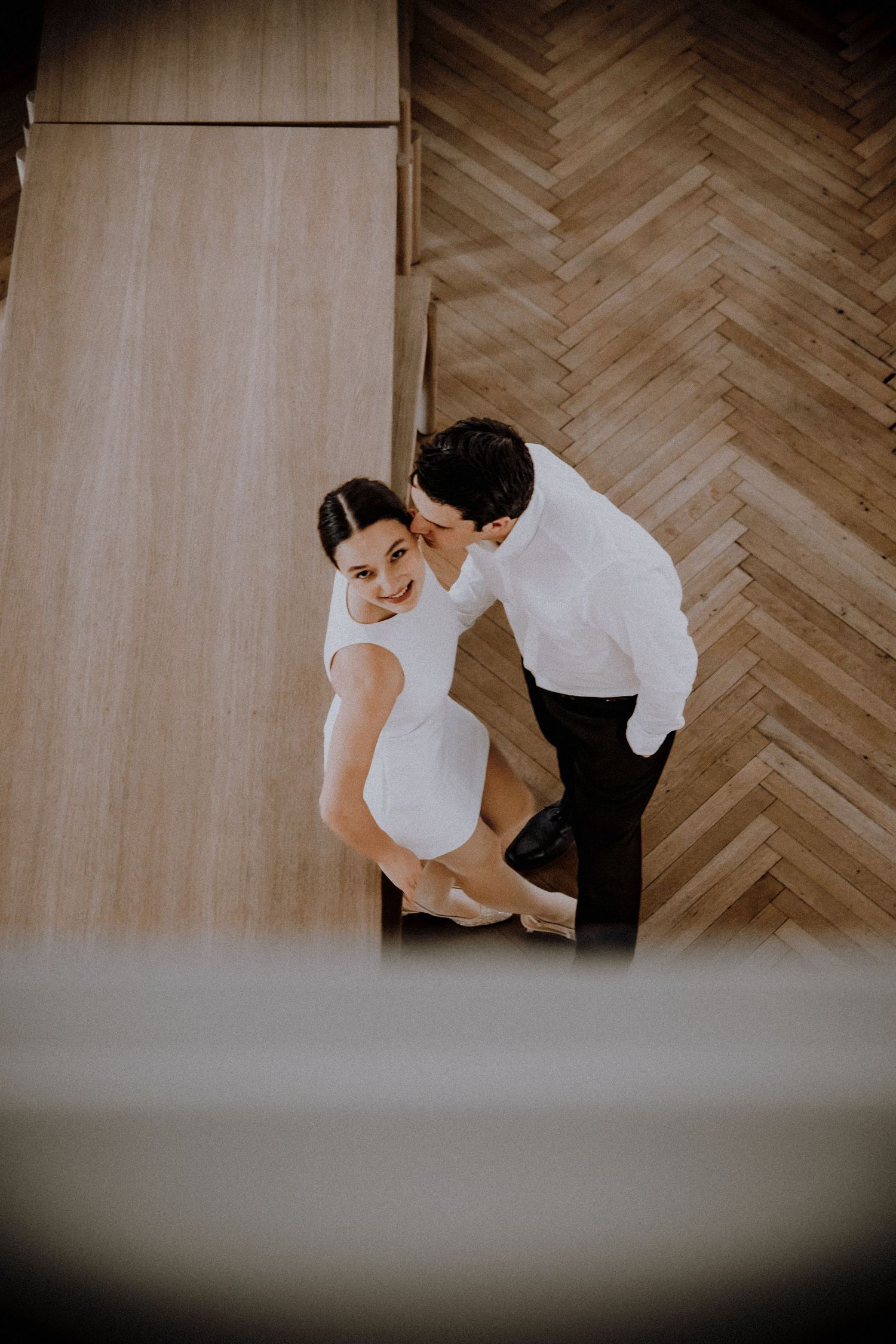 Minimalist wedding dance practice on herringbone wood flooring.