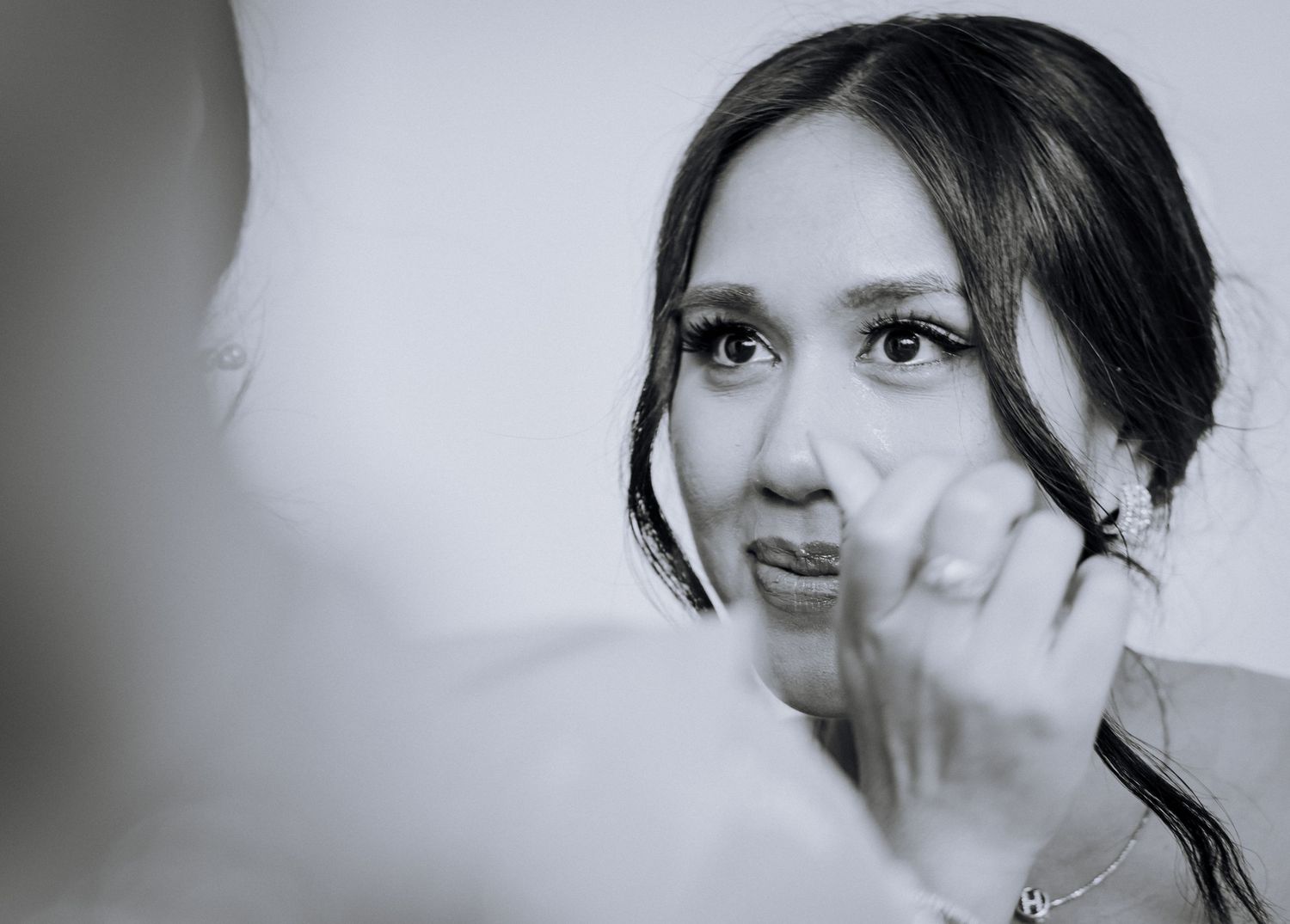 Black and white artistic portrait showing thoughtful expression with hand resting against cheek on light background.