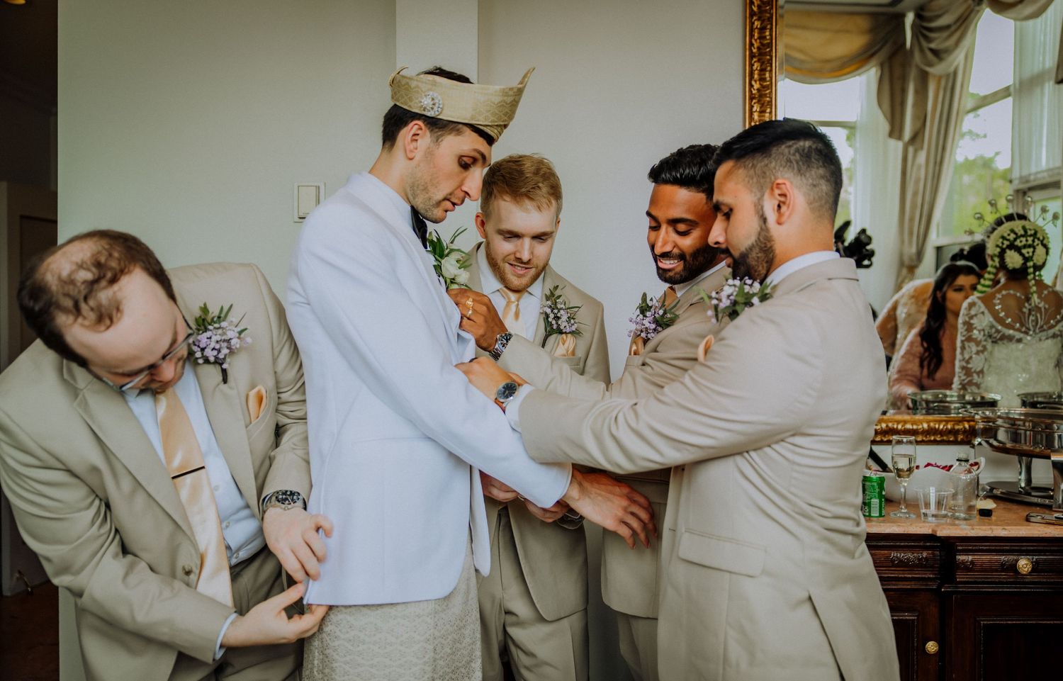 Candid photos showing groomsmen helping each other get ready on a wedding day with tan colored suits.