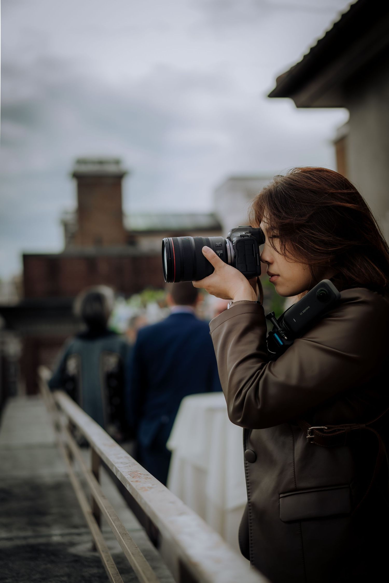 Wedding photographer capturing moments on rooftop with overcast sky.