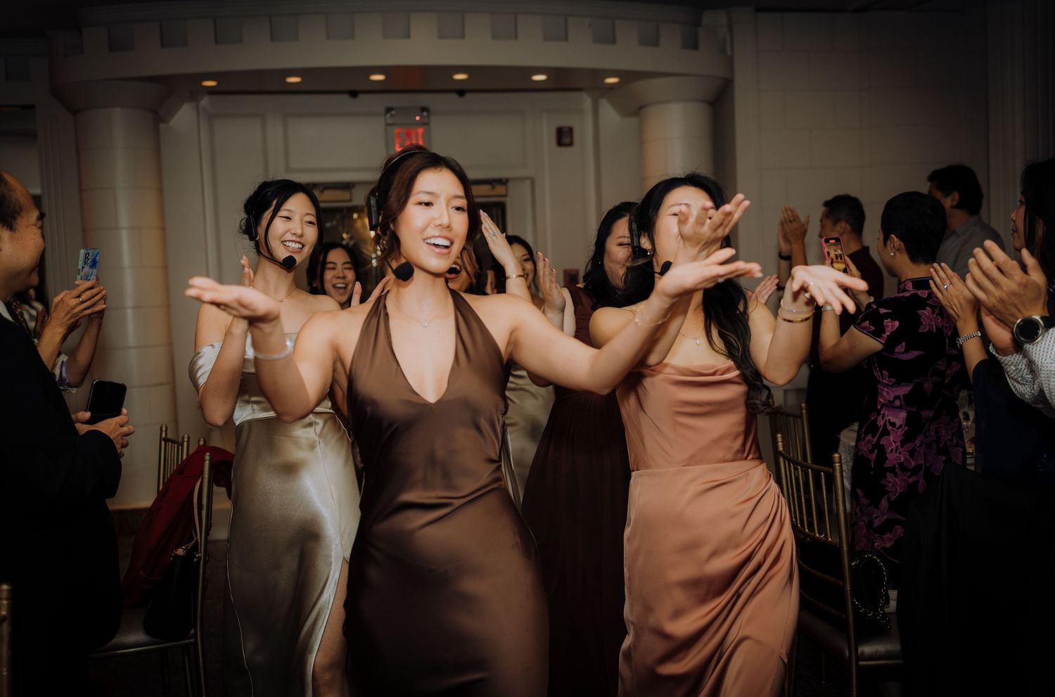 Wedding guests dancing and celebrating on a dimly lit dance floor.