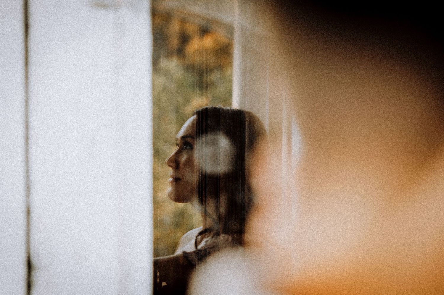 An artistic silhouette portrait through glass with soft focus and warm tones.