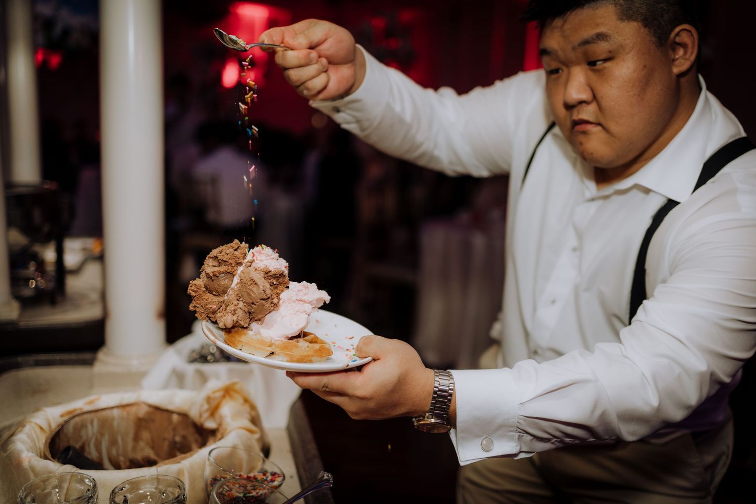 Wedding reception candid moments captured in dramatic red lighting.
