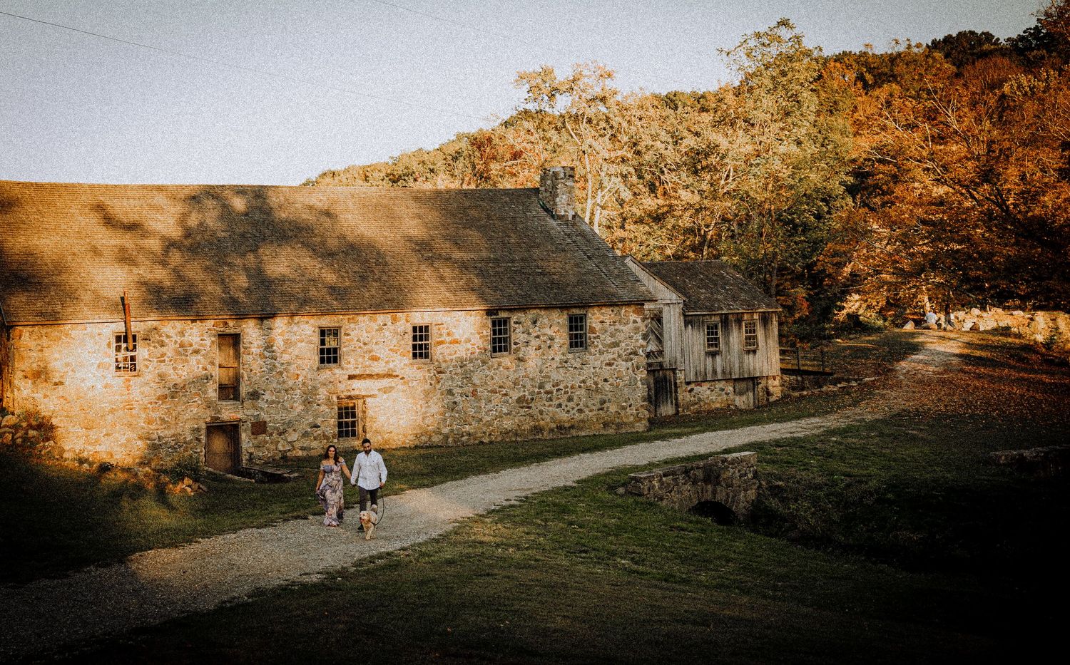 A rustic stone building captured during golden hour with autumn trees in the background.