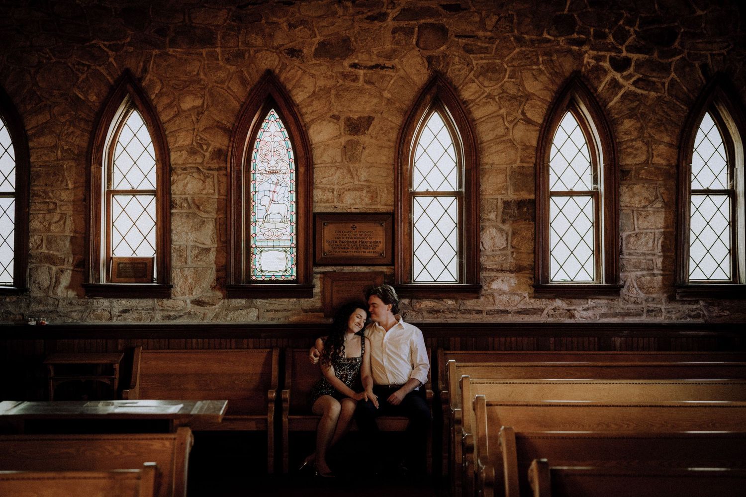 Wide view of a historic church interior with multiple arched windows and stone walls.