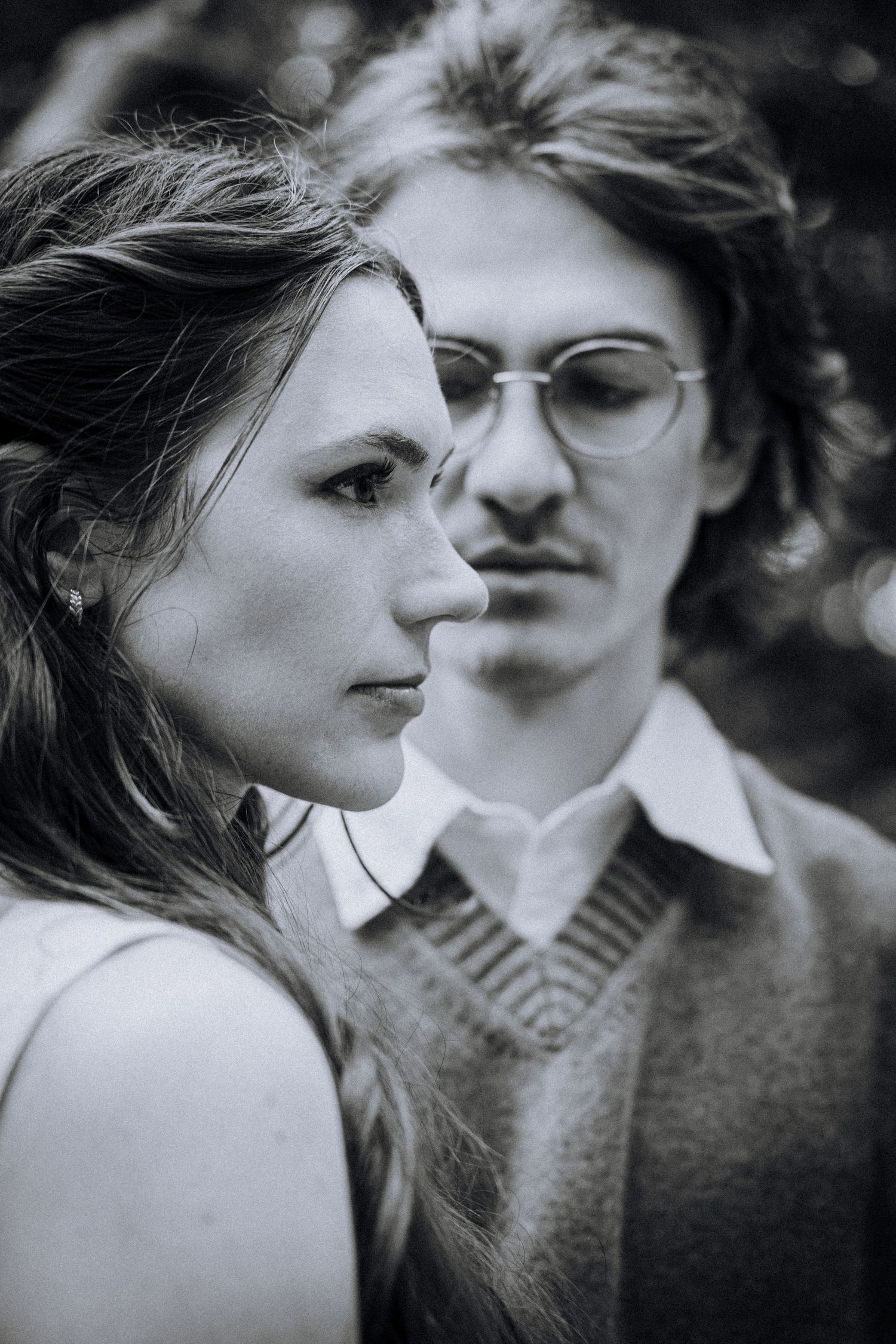 Artistic black and white portrait of a couple in vintage style with glasses and sweater.