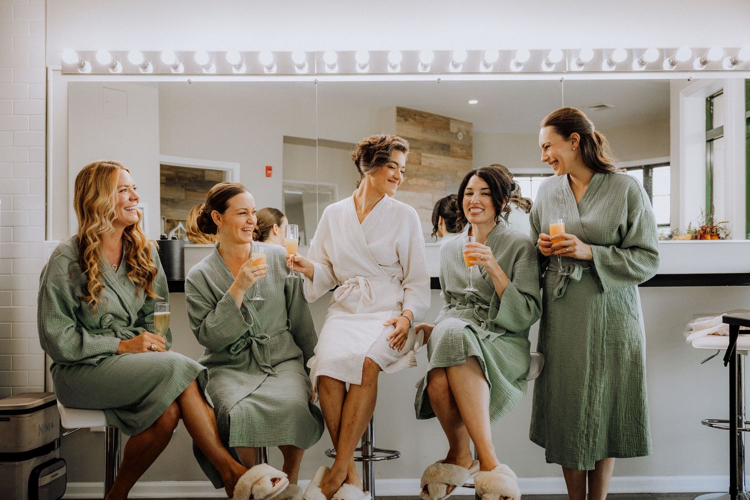 Wedding party in matching robes relaxing and chatting during preparation.