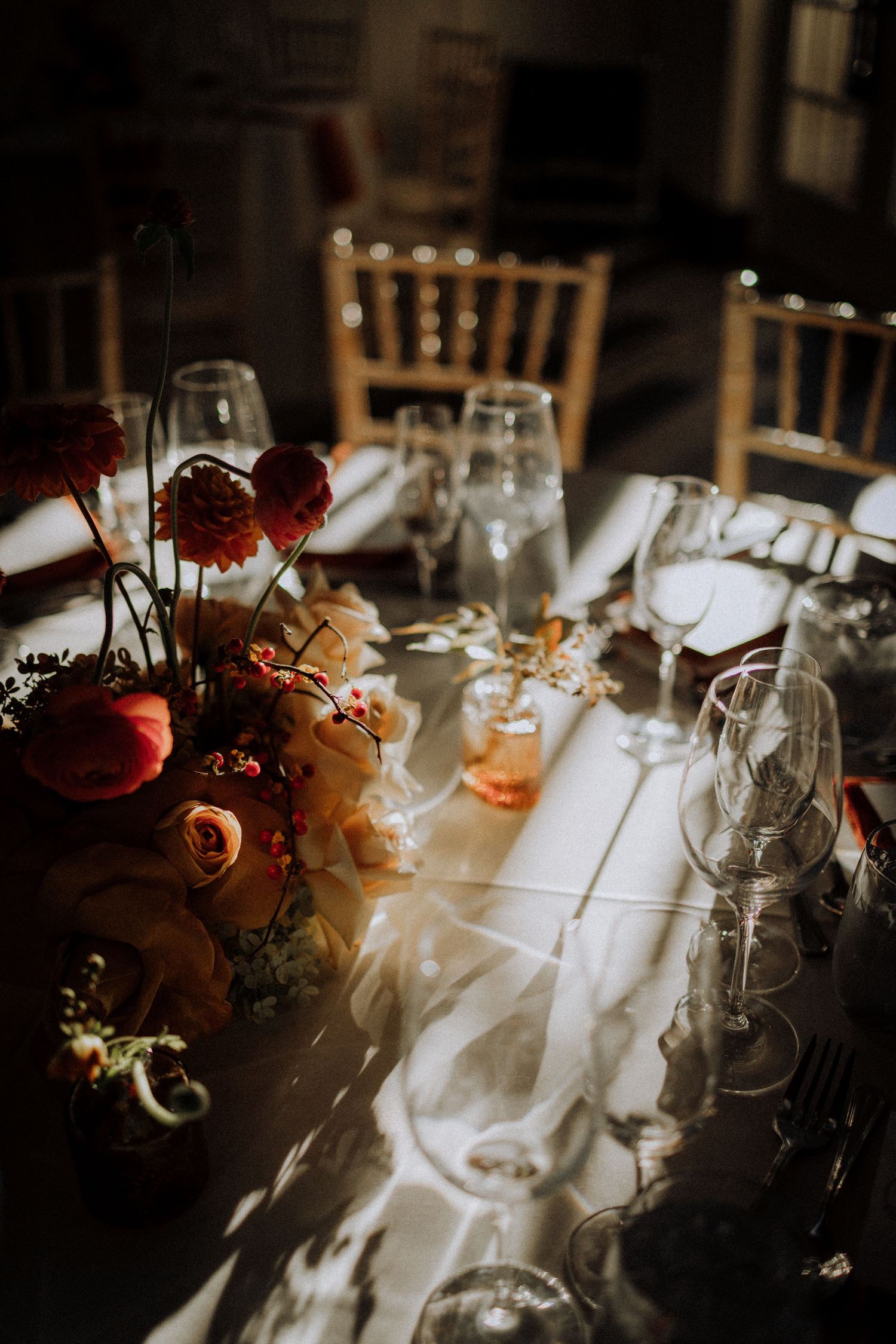 Elegant wedding reception table setting with wine glasses and floral centerpieces in warm lighting.