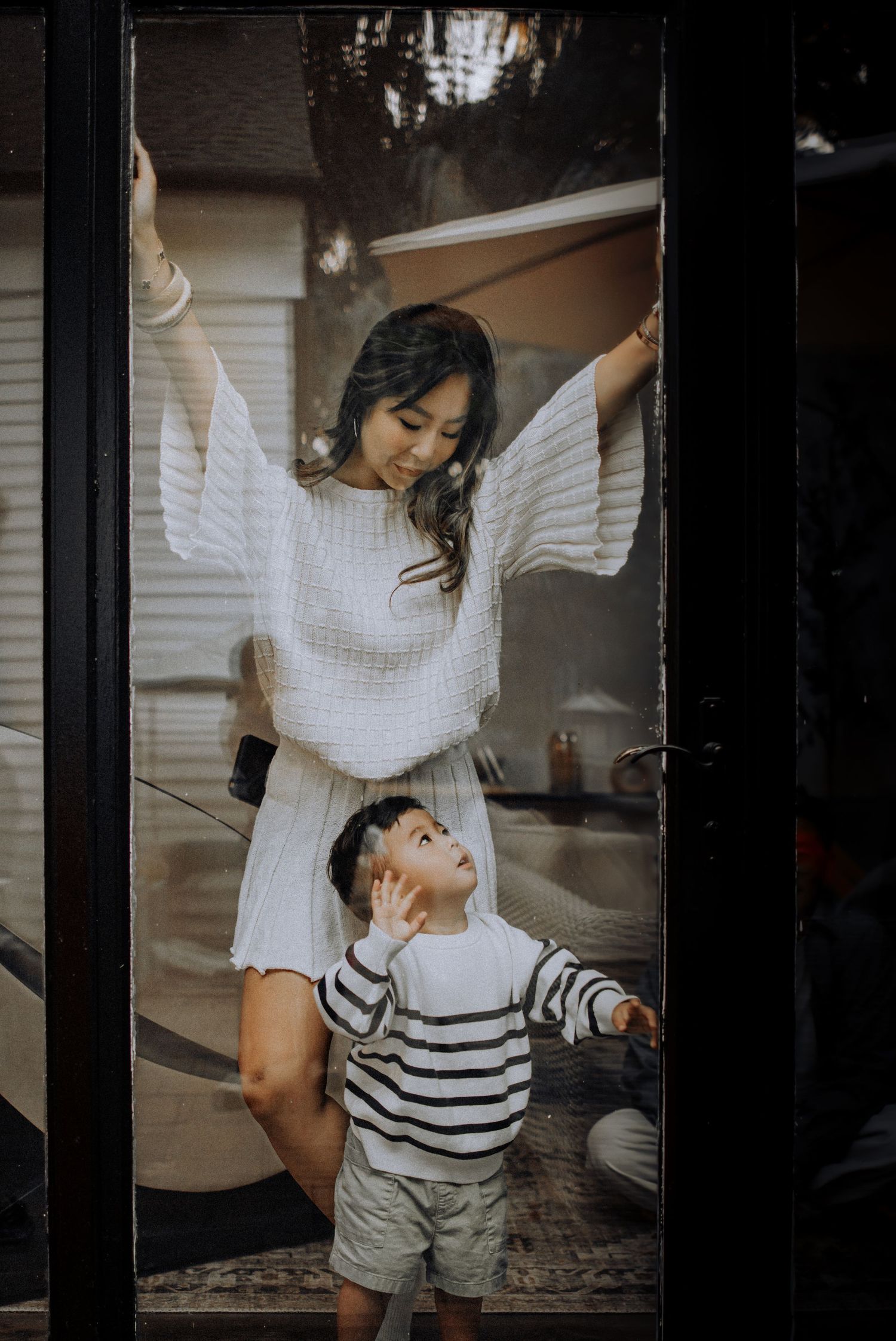 Candid lifestyle photos showing playful interaction between parent and child in white and striped clothing.