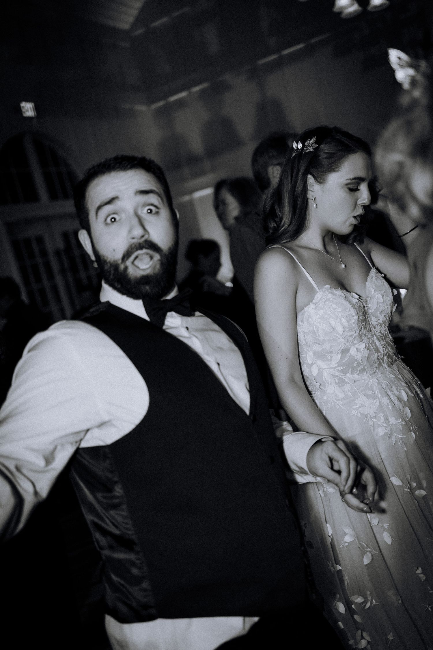 Wedding reception candid showing energetic dancing and celebration in black and white.