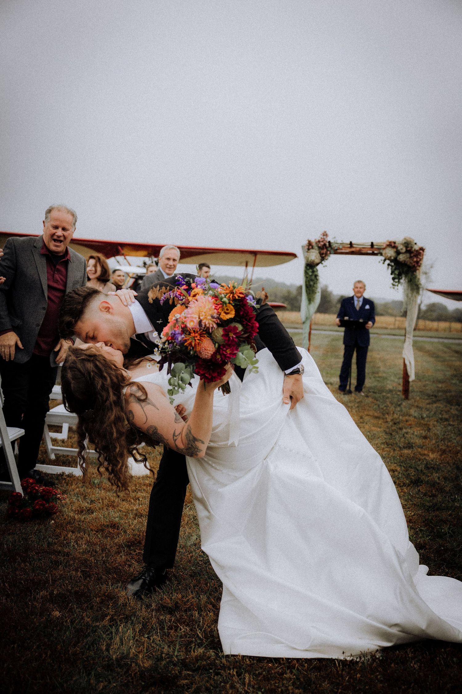 Bride in flowing white dress twirls during outdoor wedding celebration.