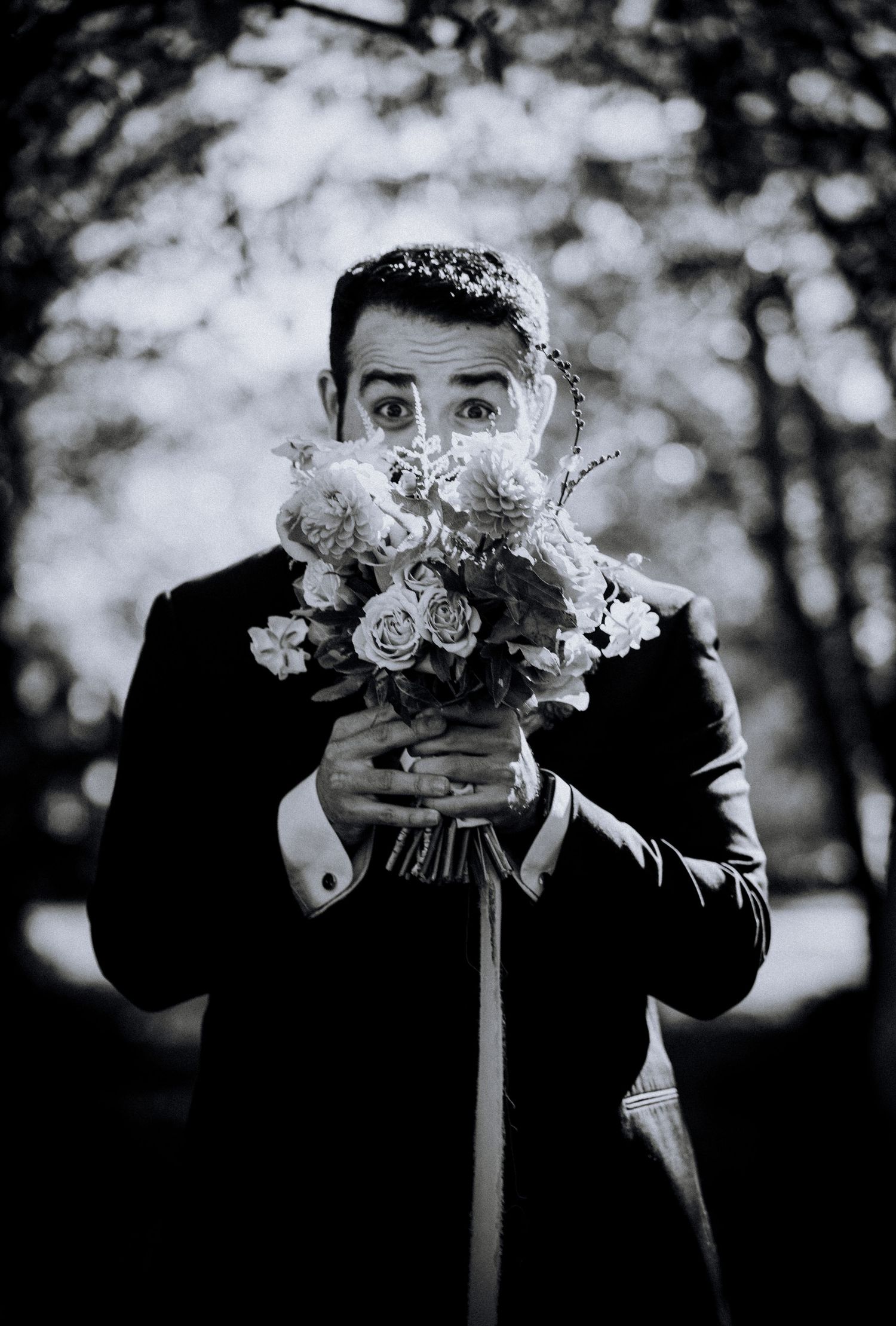 Black and white portrait series of wedding bouquet held against formal attire.
