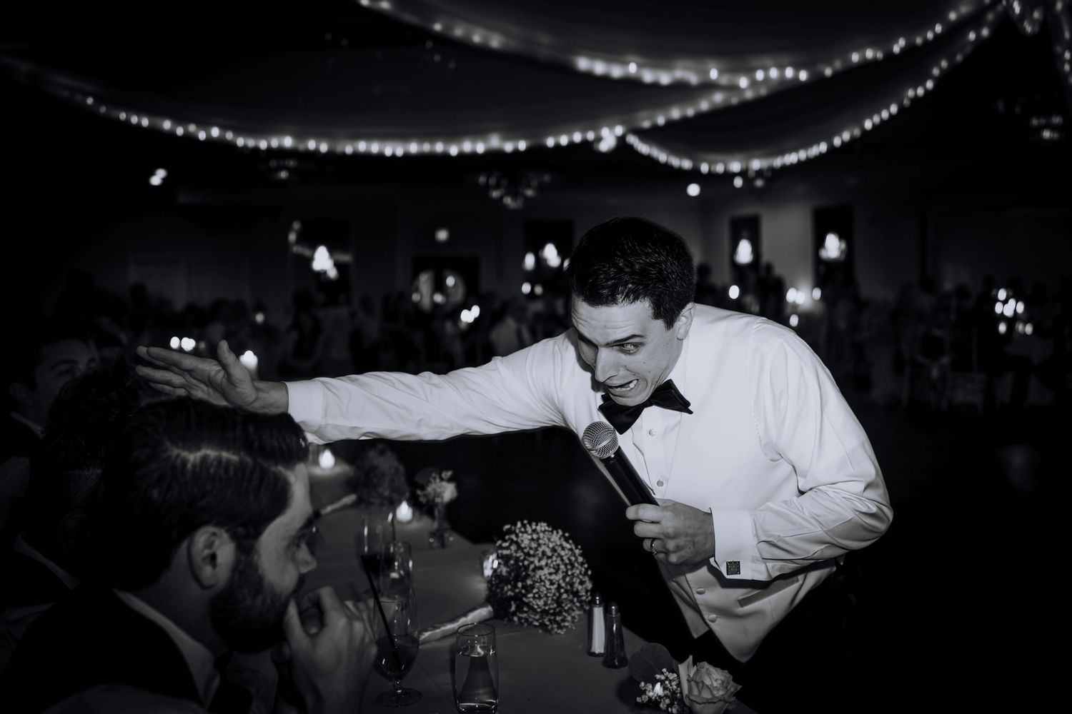 Guests celebrating at a wedding reception under twinkling string light decorations.
