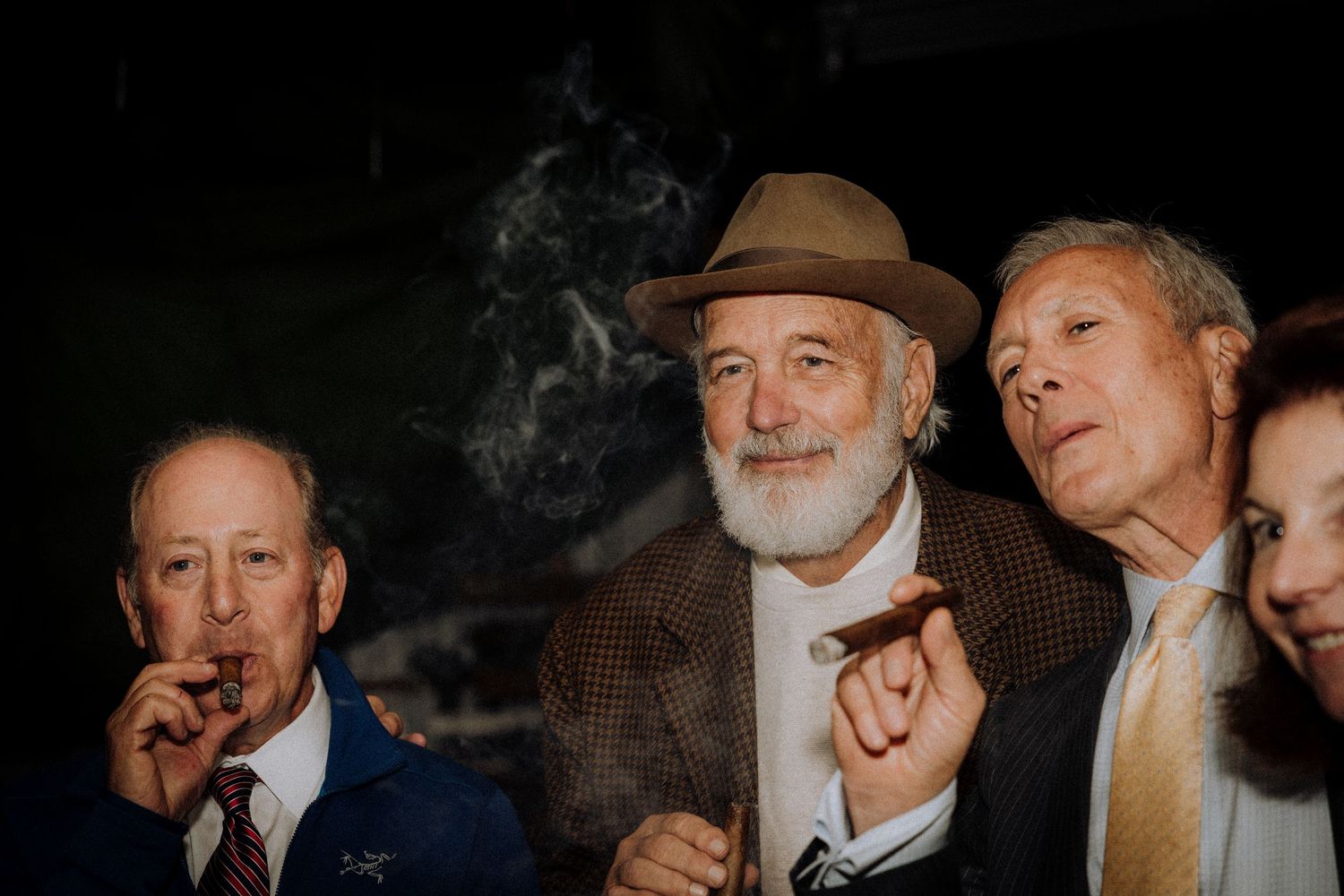 A group of wedding guests share laughter in dramatic low-light conditions.