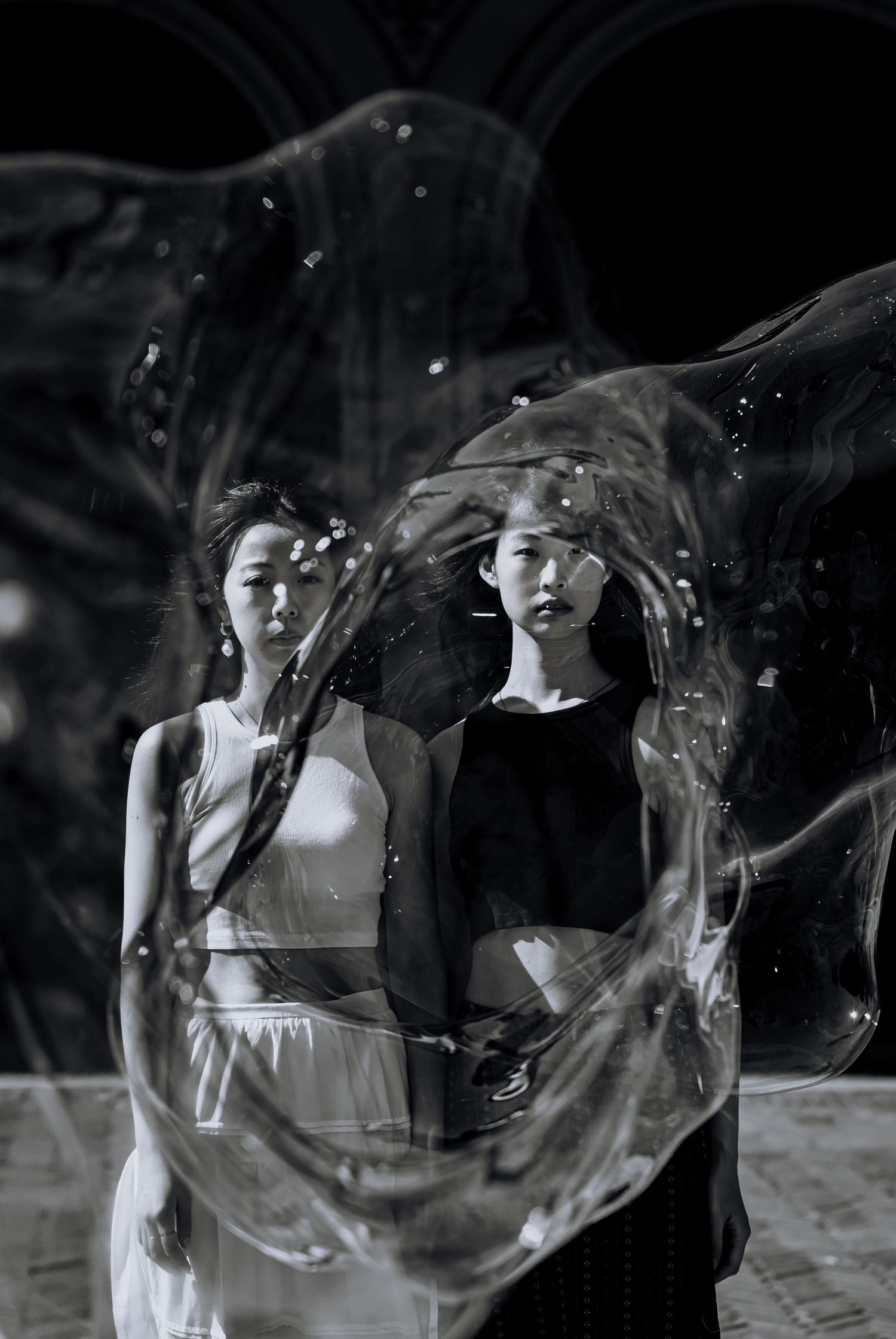 Artistic black and white portrait with flowing fabric creating ethereal effect.