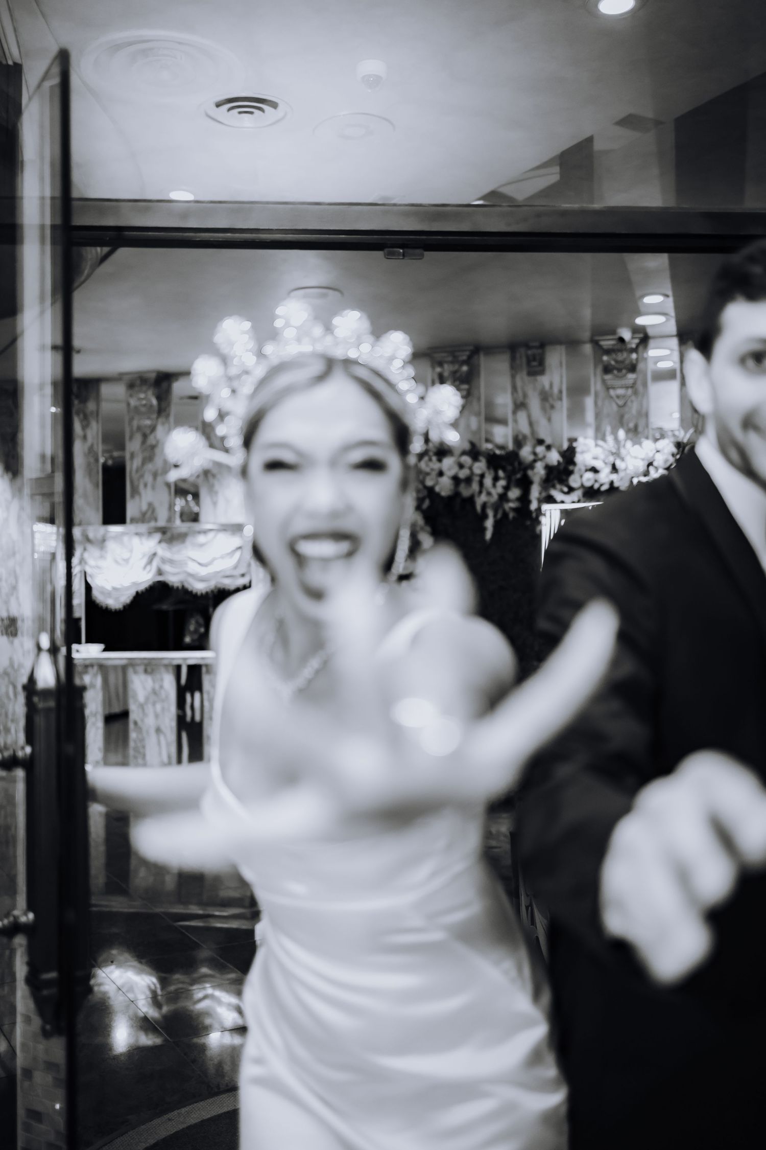 Black and white photo series showing a bride dancing joyfully at a wedding reception in a white dress and veil.