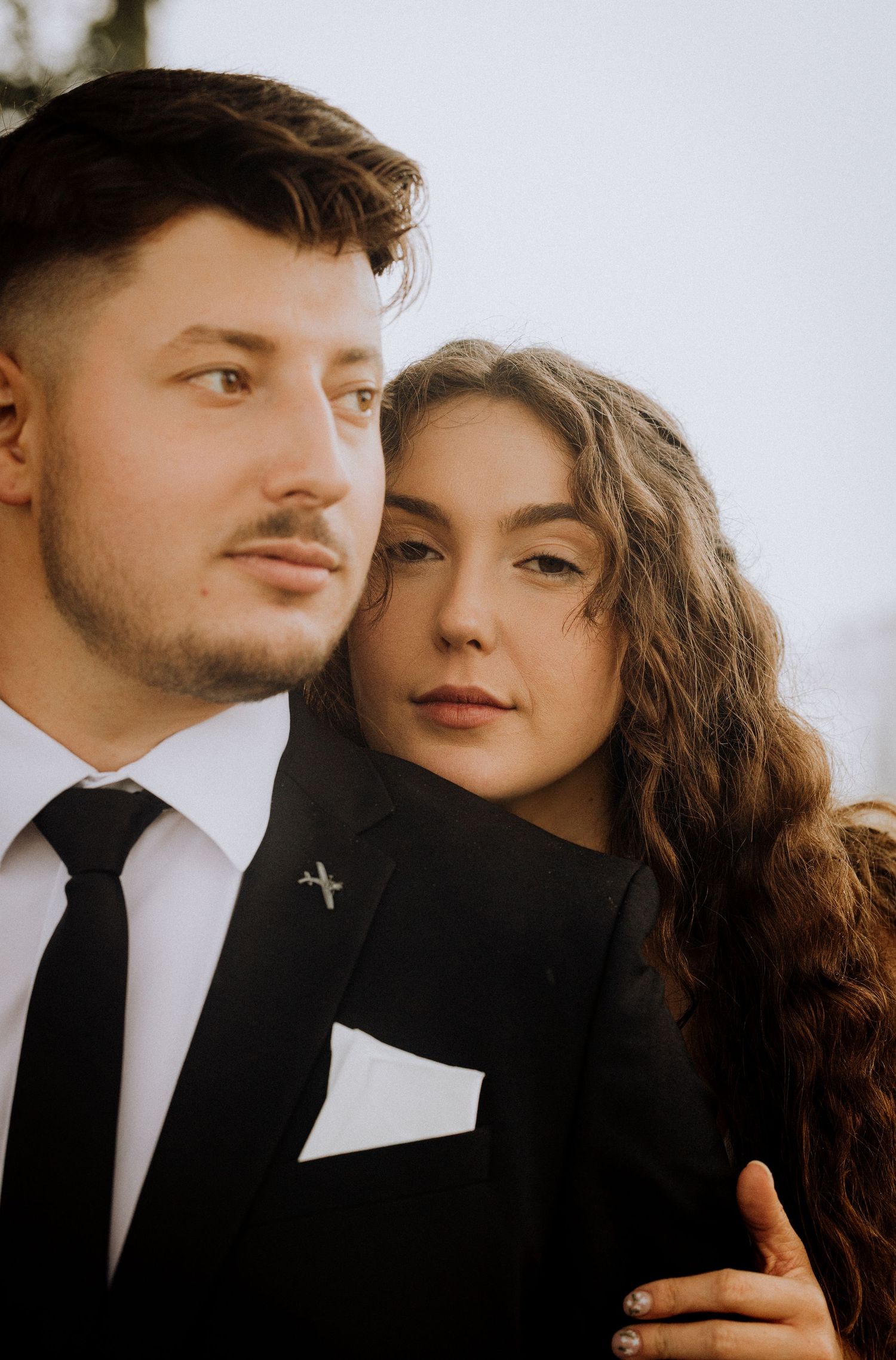 An intimate portrait of a couple in formal attire against a bright white background.