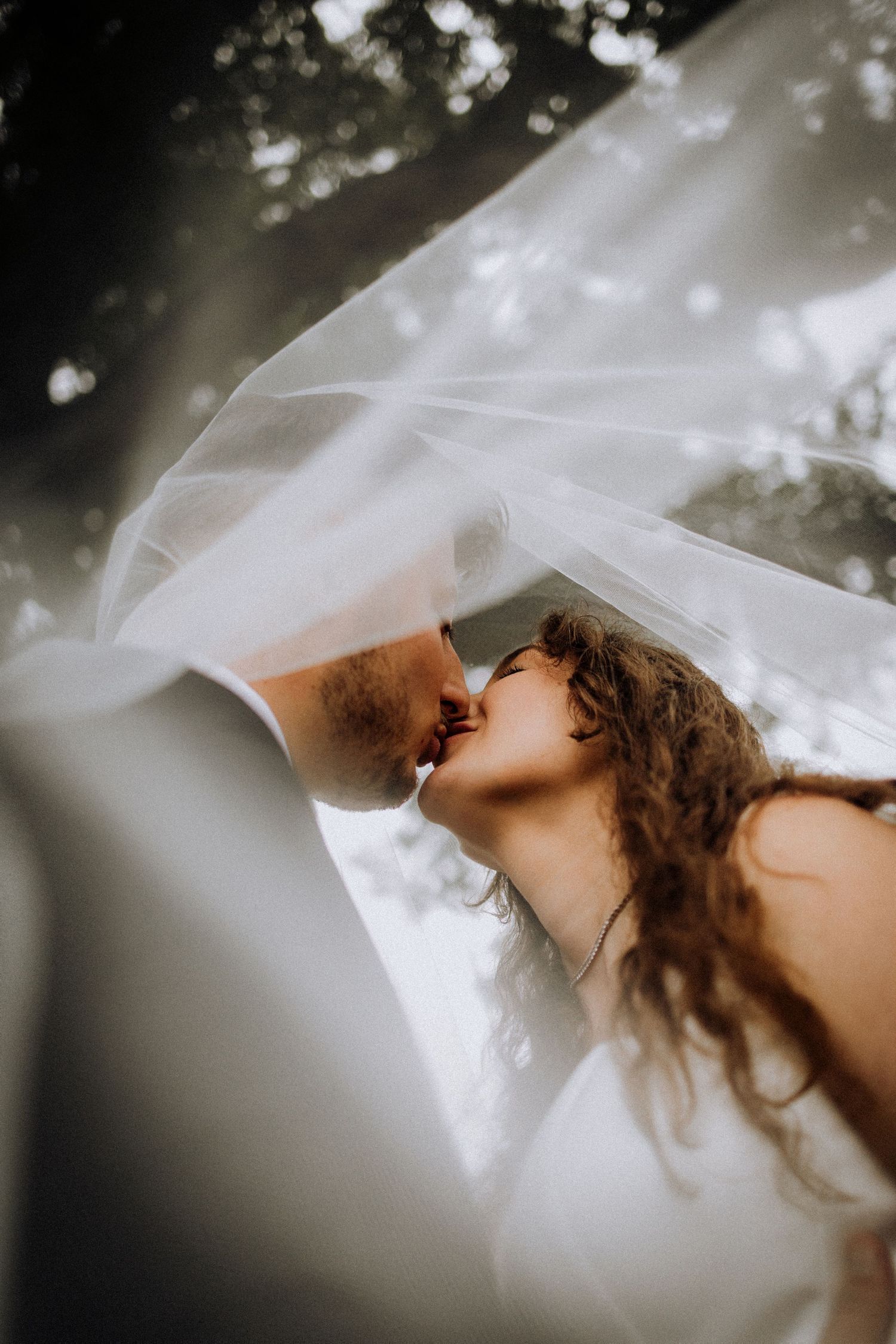 Delicate white bridal veil flows gracefully in the wind against a soft bokeh background.