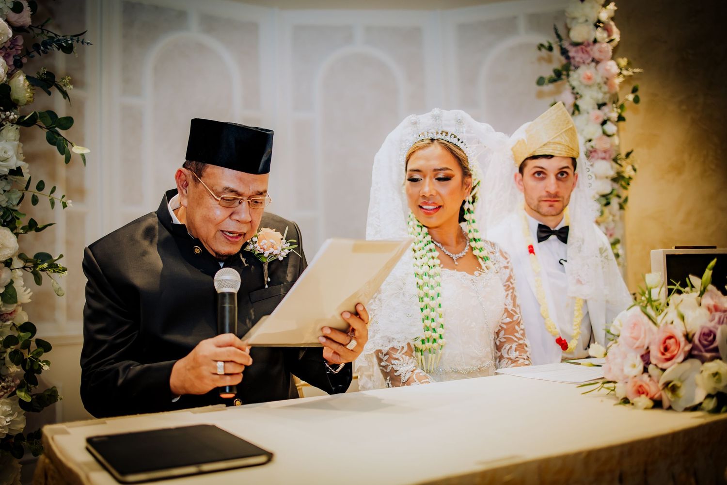 Guests toasting and celebrating at an elegant wedding reception table decorated with floral arrangements.