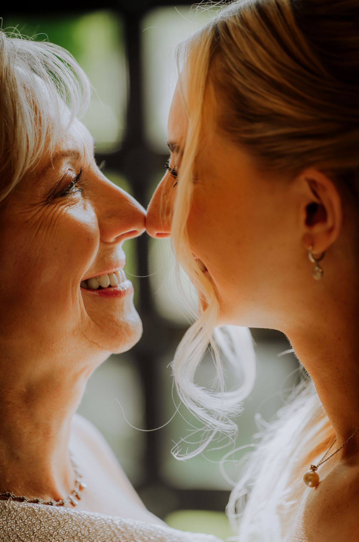 A tender close-up portrait of two generations sharing an intimate nose-to-nose moment while smiling.