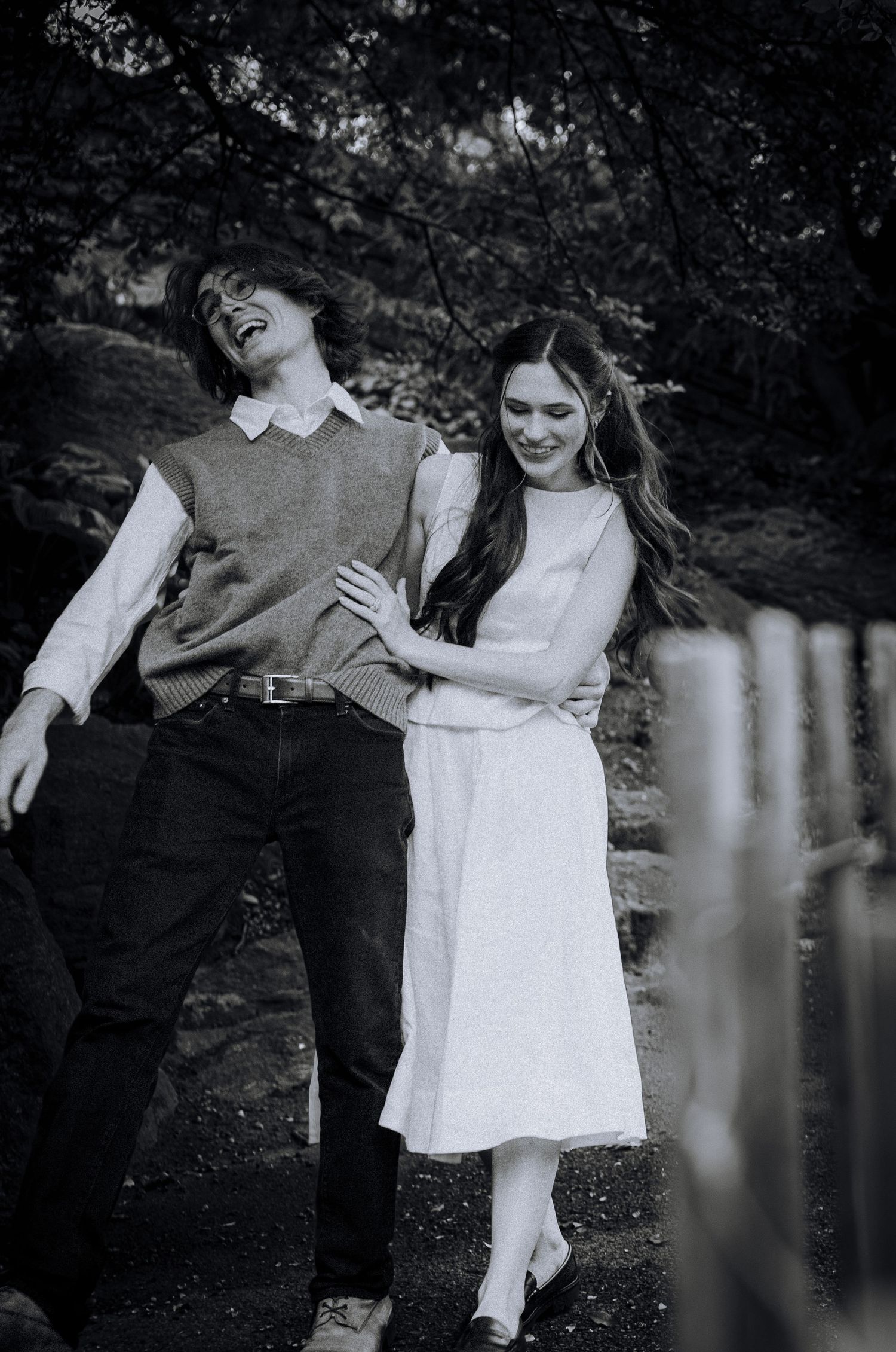 Black and white photos of playful couple interactions near a wooden fence.