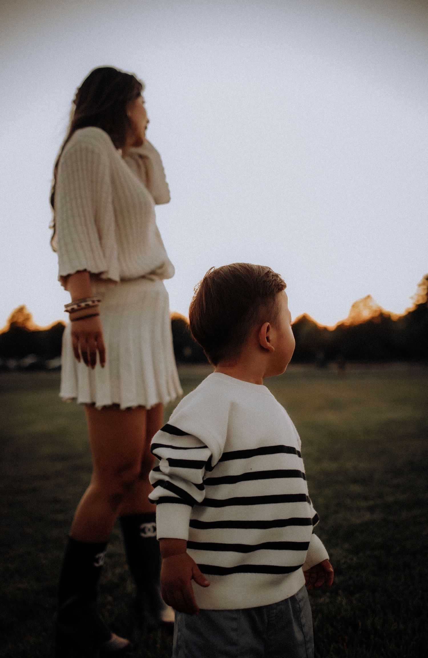 Silhouettes of people in white clothing against a sunset backdrop in a grassy field.