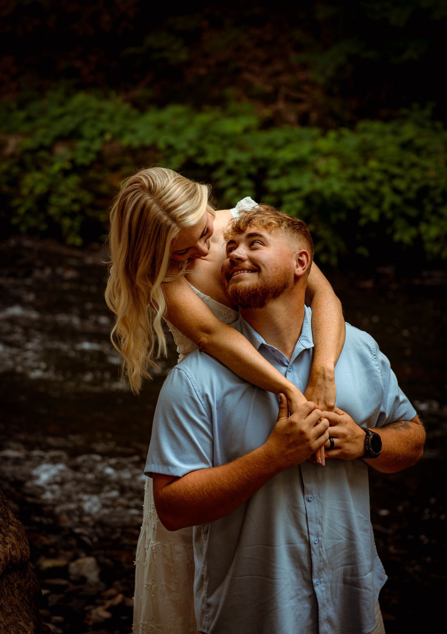 Playful couple embracing and laughing together in a natural outdoor setting.