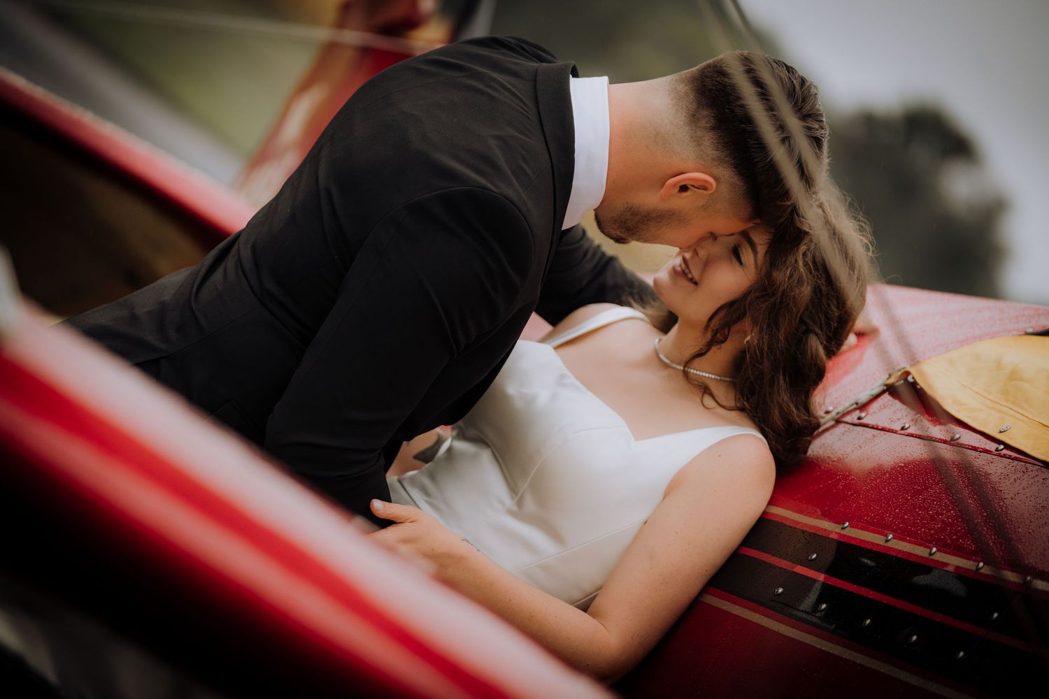 Close-up shot of couple sharing intimate moment near vintage aircraft.