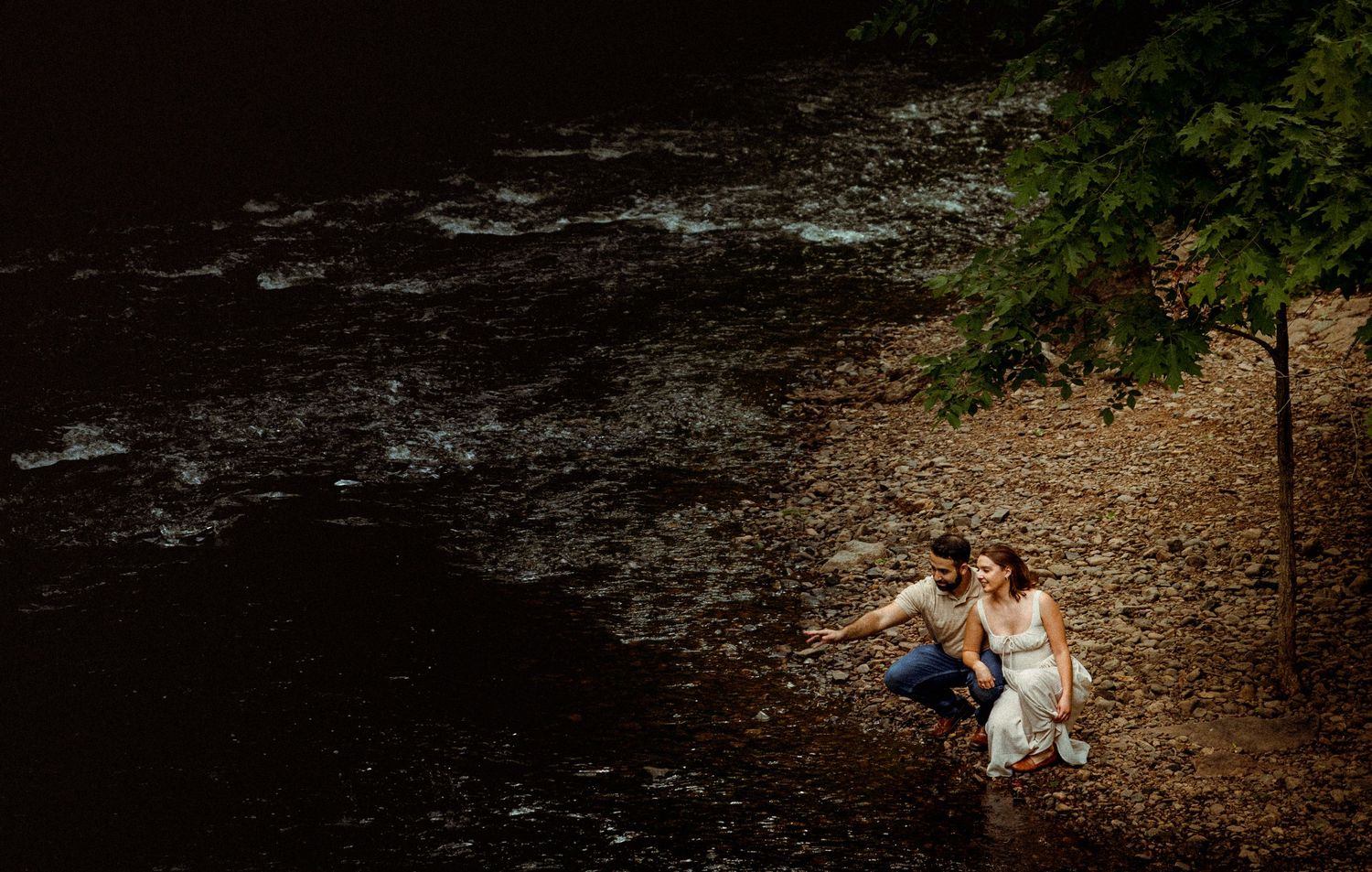 Artistic engagement photos captured in a serene forest setting with a stream backdrop.