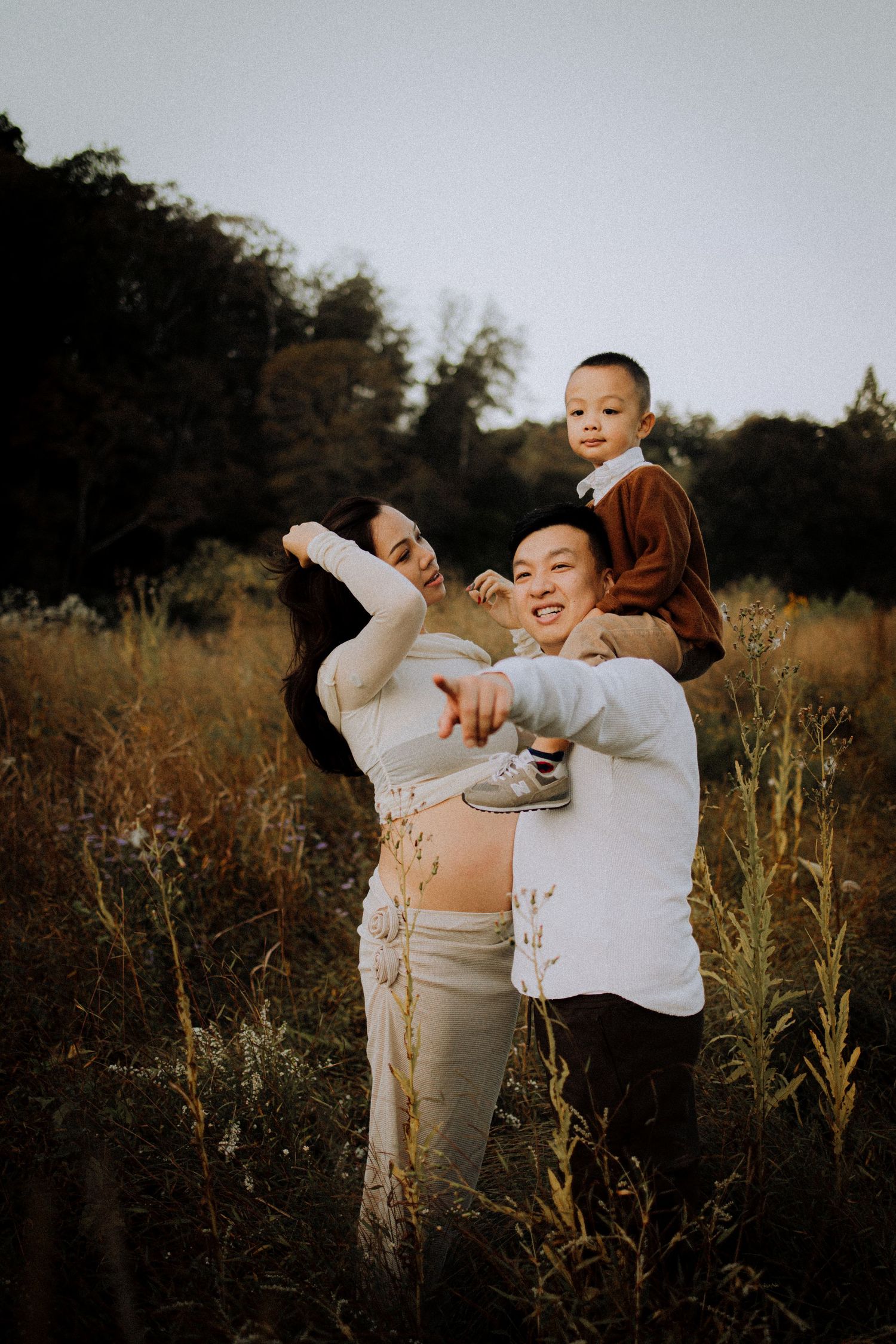 Family sharing joyful laughter during outdoor portrait session at dusk.