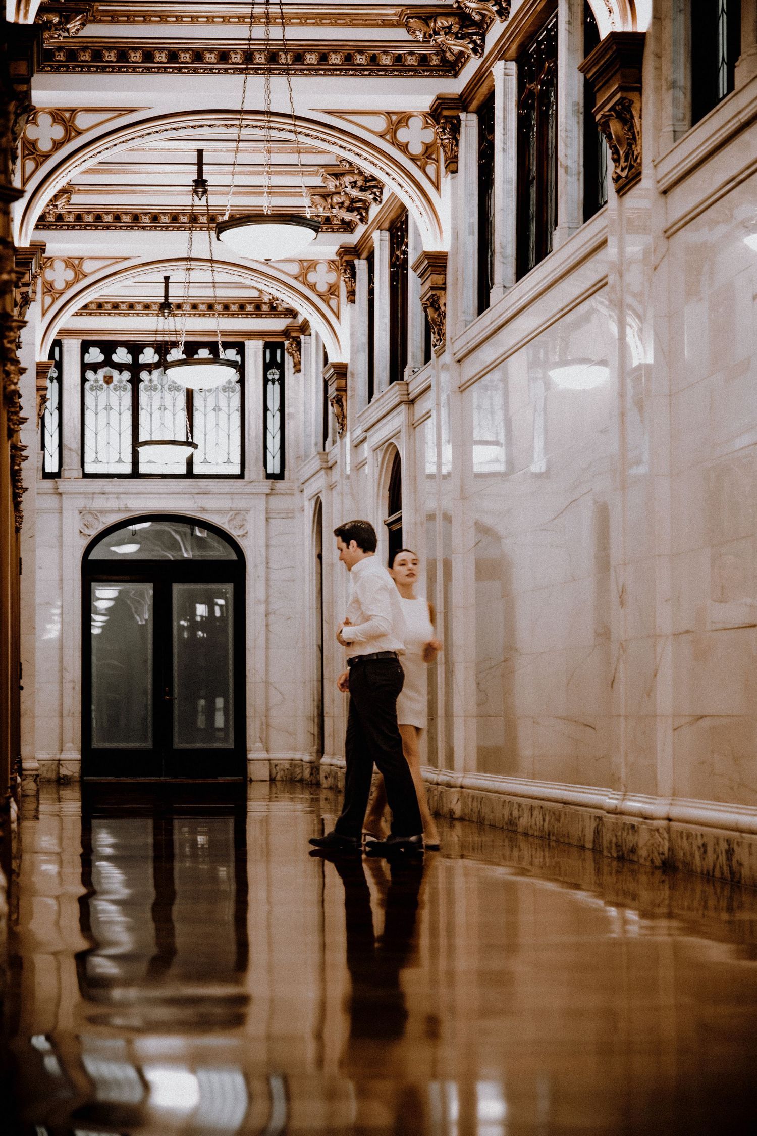 A long elegant corridor with ornate ceiling details and polished floors.