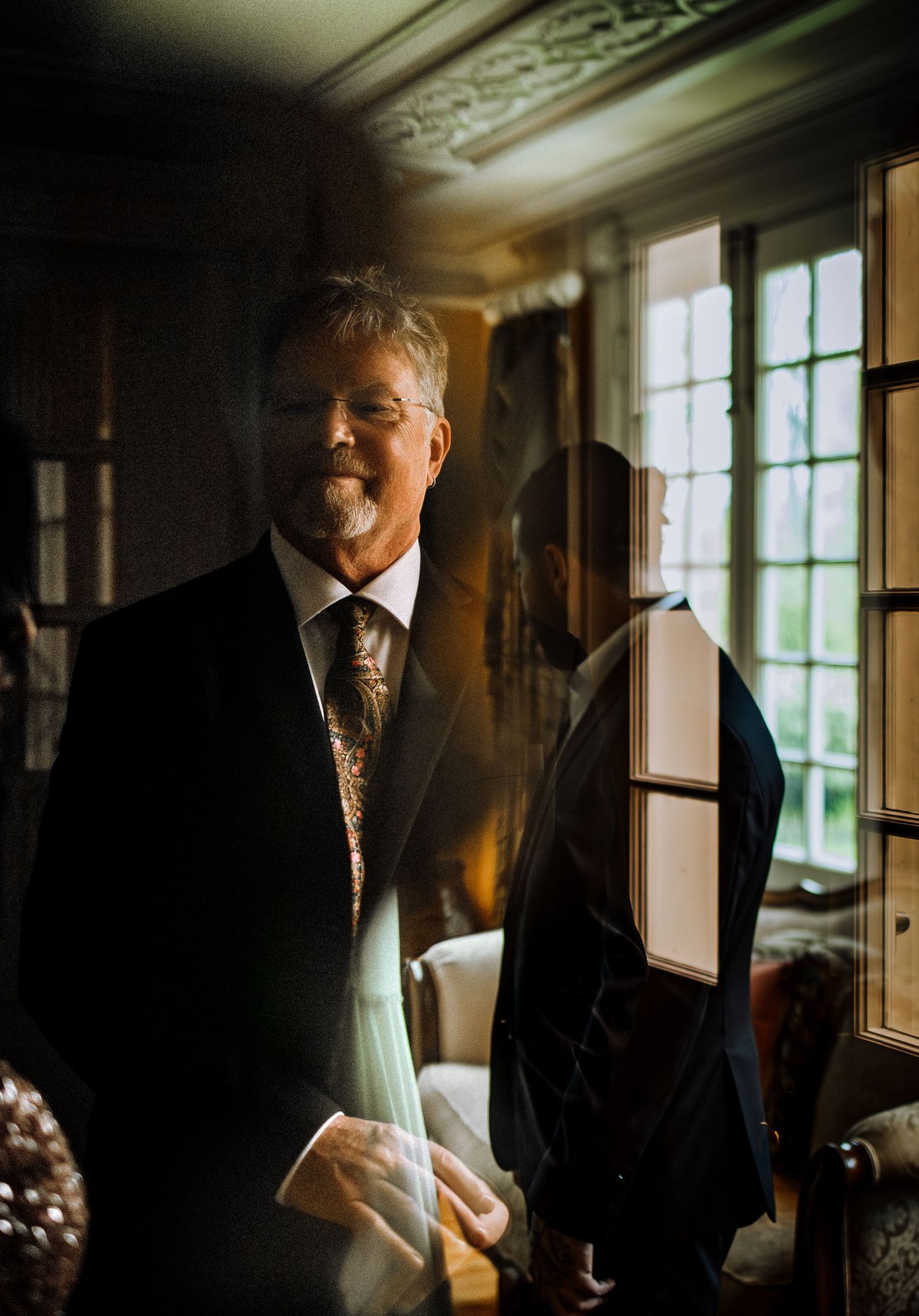 Moody indoor wedding preparation photos with natural window lighting and formal attire.