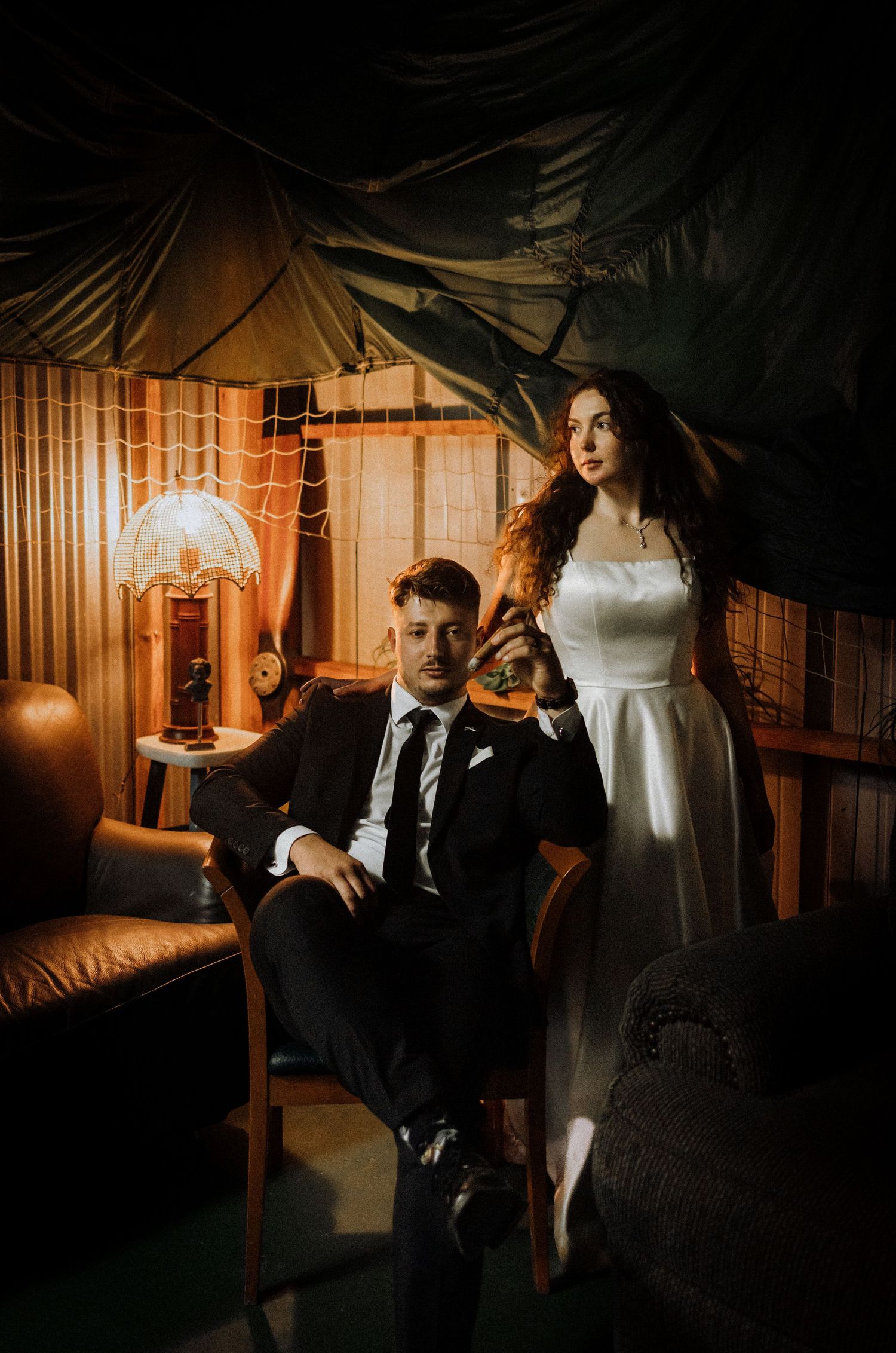 Moody vintage-style wedding scene in warm lighting with elegant formal attire.