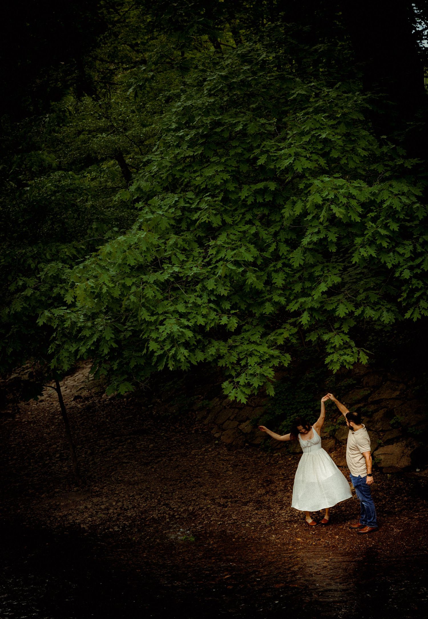Romantic forest photography session with natural lighting filtering through dense green foliage.