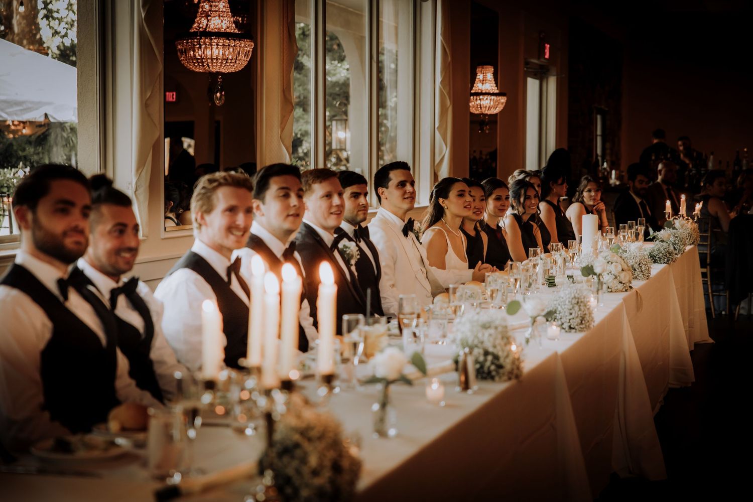 Elegant wedding reception table settings with glowing chandeliers and formal place settings.