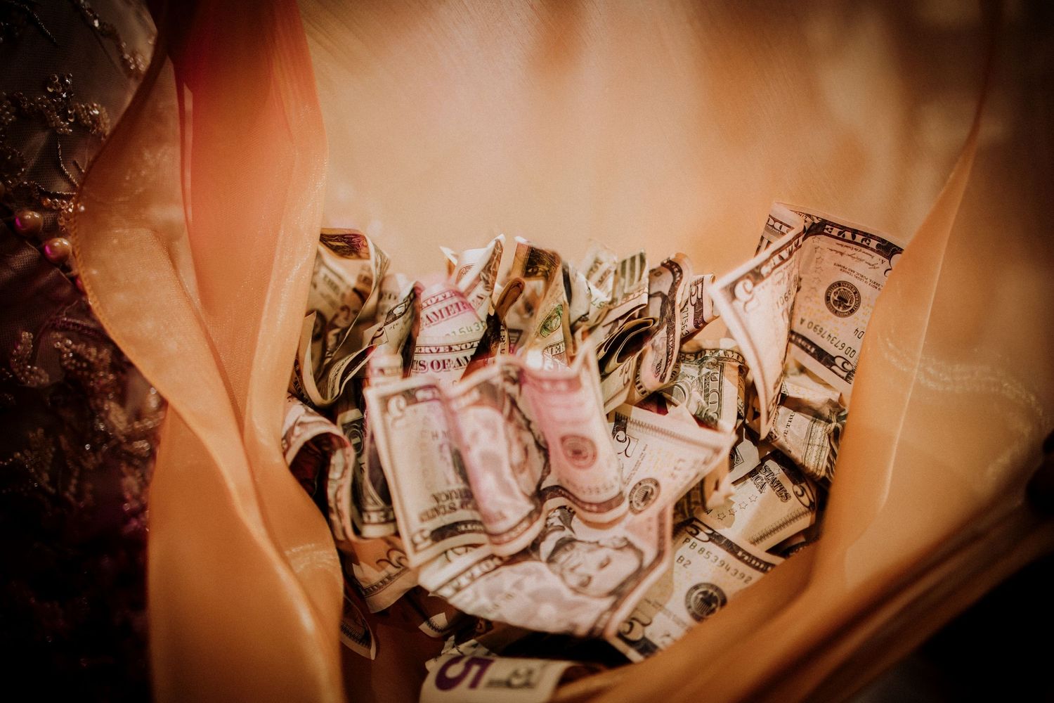 Crumpled US dollar bills photographed with an artistic brown filter effect and shallow depth of field.