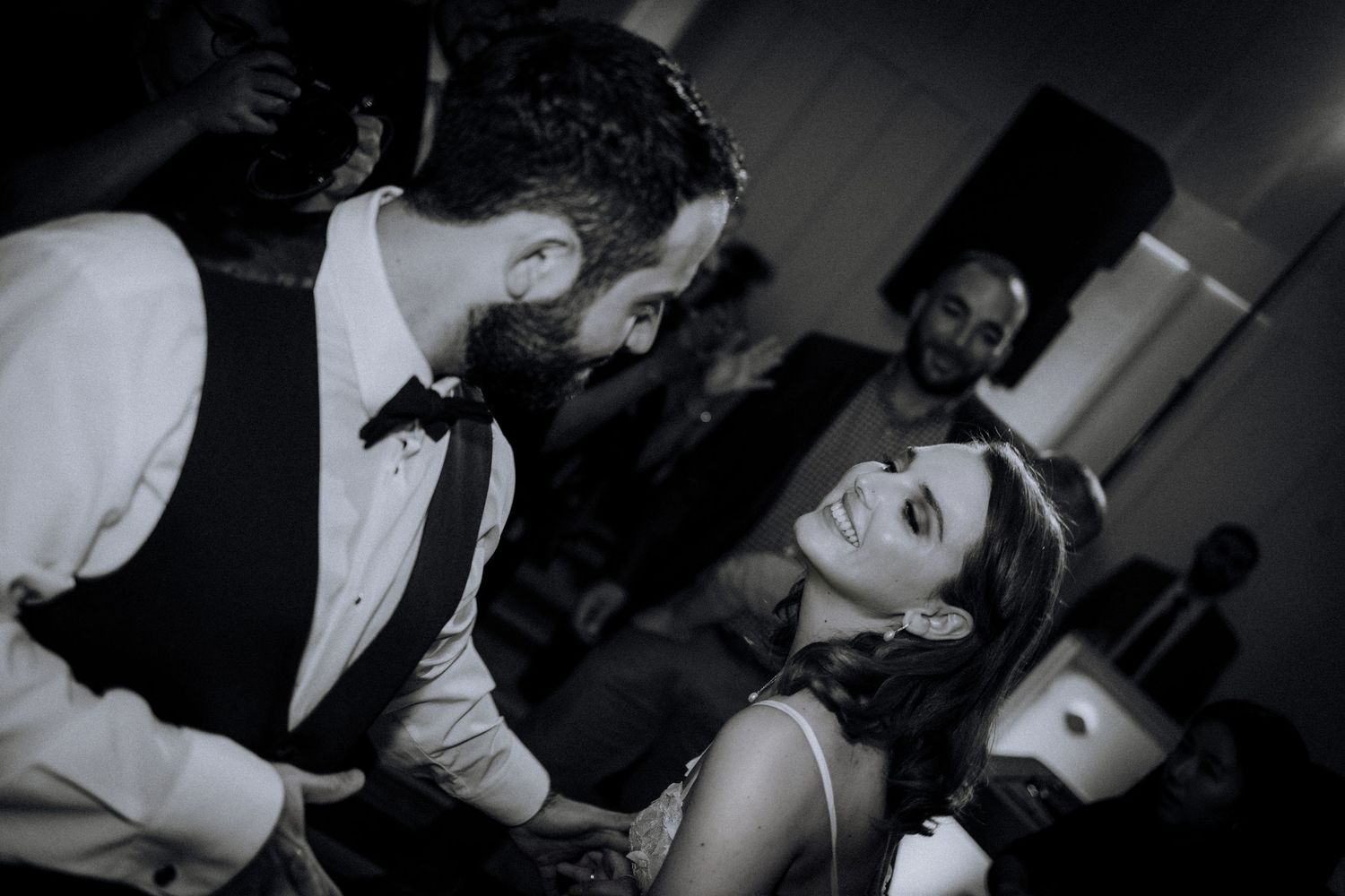Black and white photo of a couple sharing a joyful moment during their wedding dance.