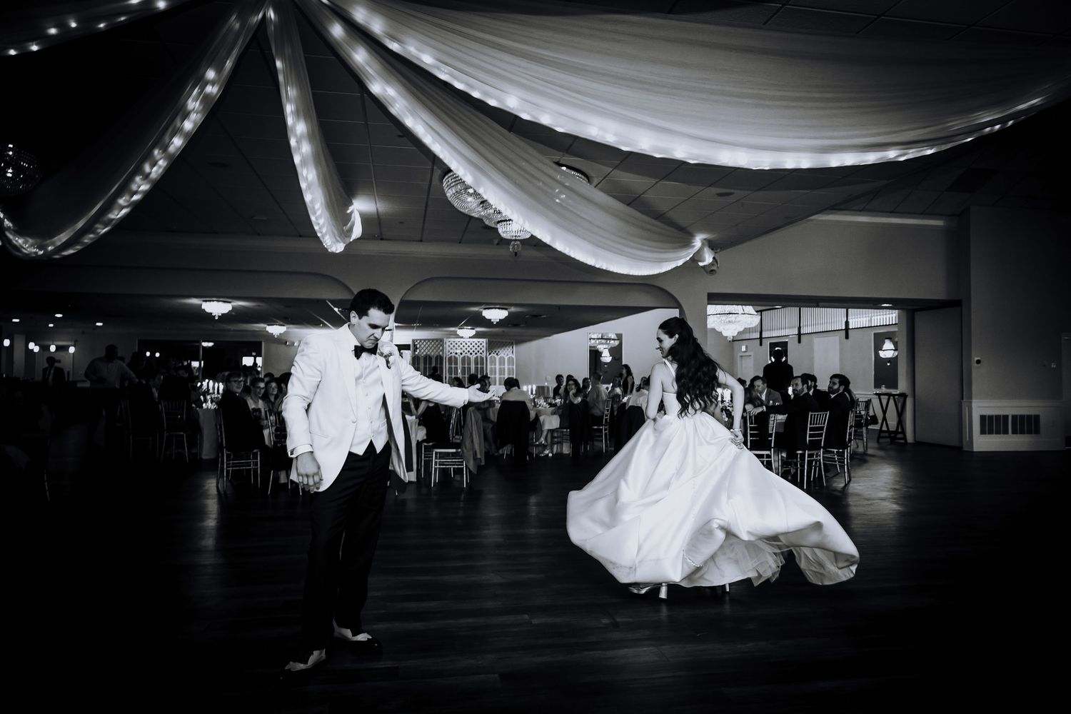 Black and white wide shot of a wedding reception venue with dramatic lighting and decor.